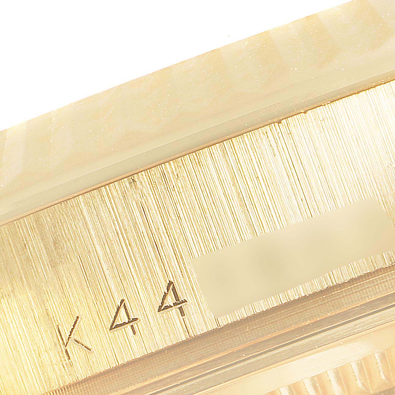 This image shows a close-up of the engraved serial number and fluted bezel on a Rolex President 118238 Men's Yellow Gold Champagne Dial 118238 Men's Yellow Gold Champagne Dial model watch.