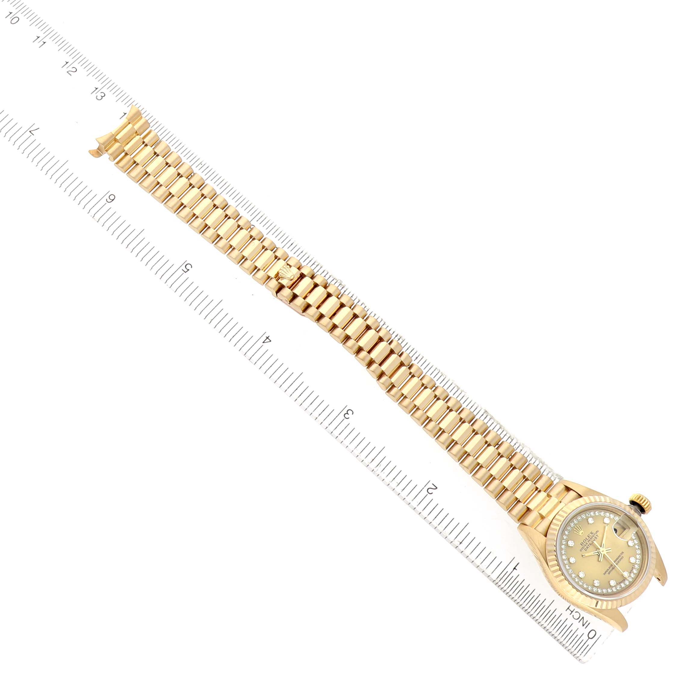 The image shows a Rolex President 69178 Women's Yellow Gold Champagne Dial watch from a top-down angle, displaying the full bracelet and face along a ruler for scale.
