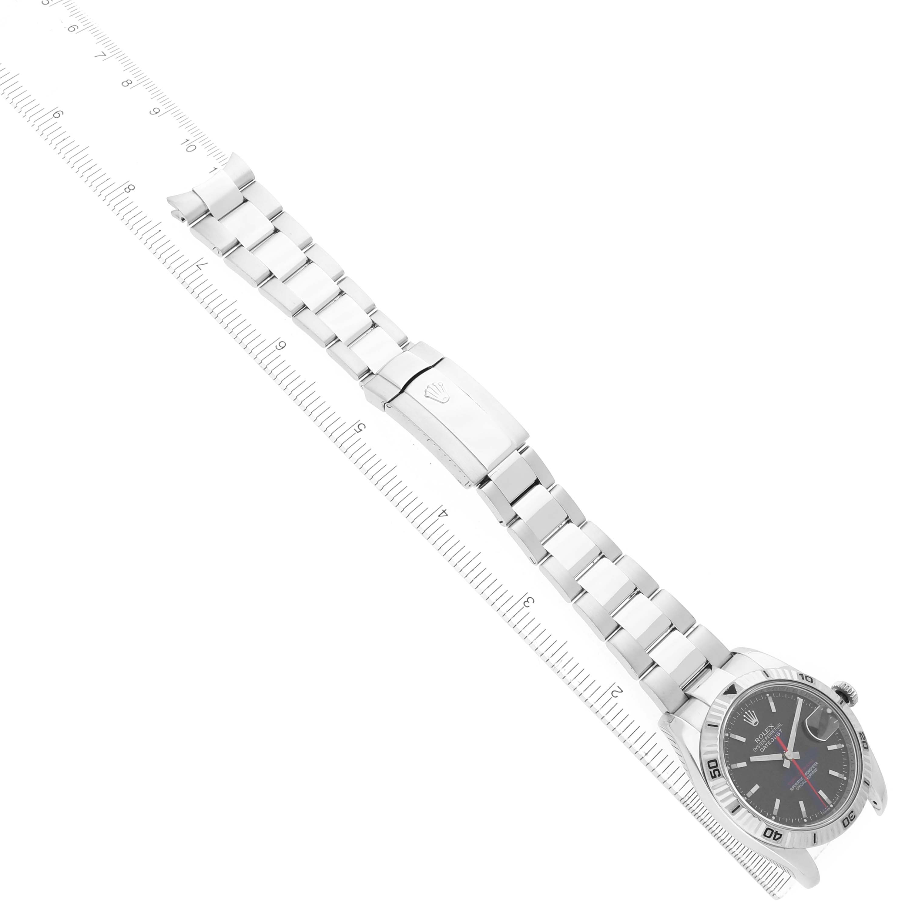 The Rolex Turn-o-Graph 116264 Men's Stainless Steel Black Dial watch is shown from a side angle, displaying the bracelet, clasp, and watch face aligned with a ruler.