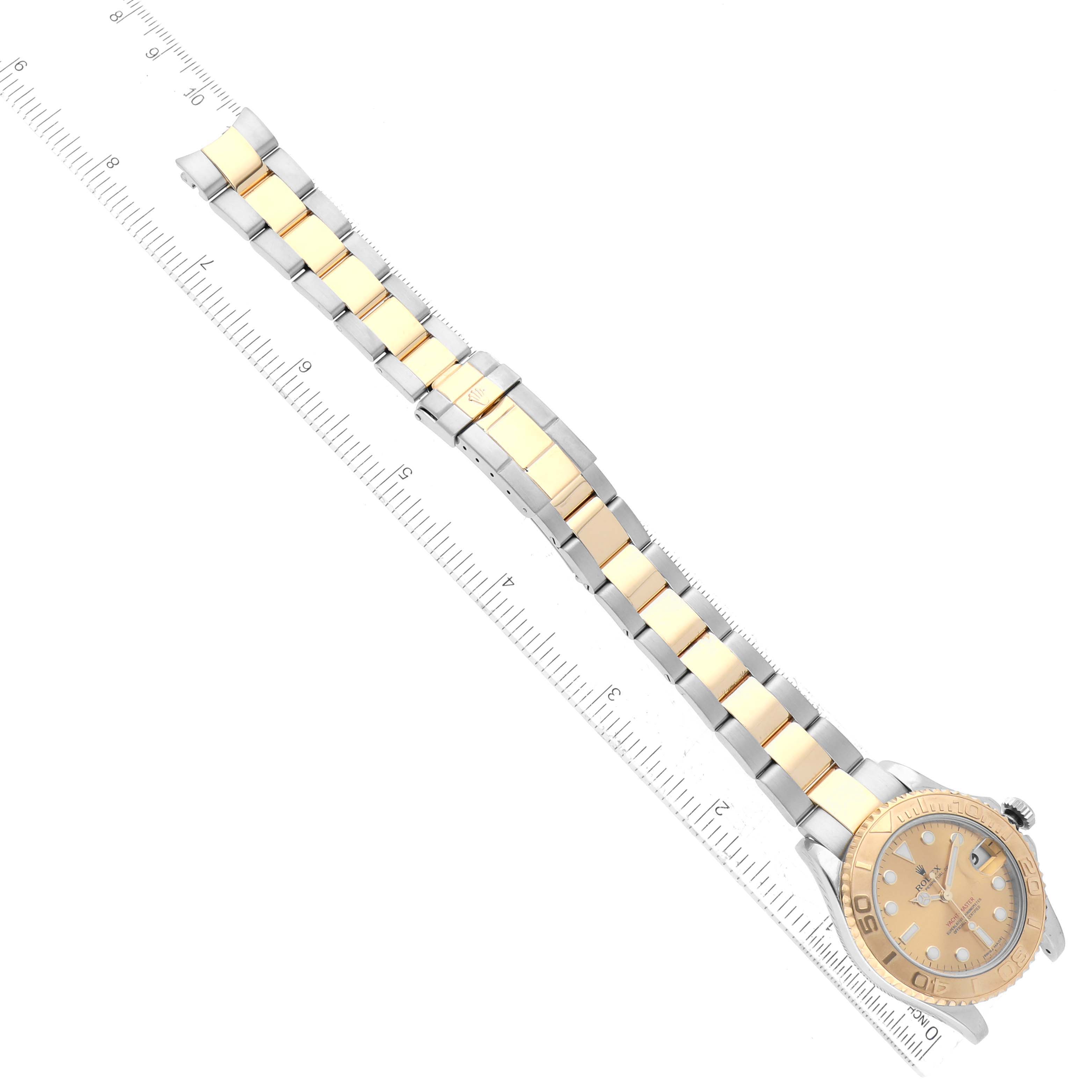 The image shows a Rolex Yacht-Master 168623 Men's Steel and Gold (two tone) Champagne Dial 168623 Men's Steel and Gold (two tone) Champagne Dial watch viewed from above, displaying the full band and face alongside a measuring ruler.