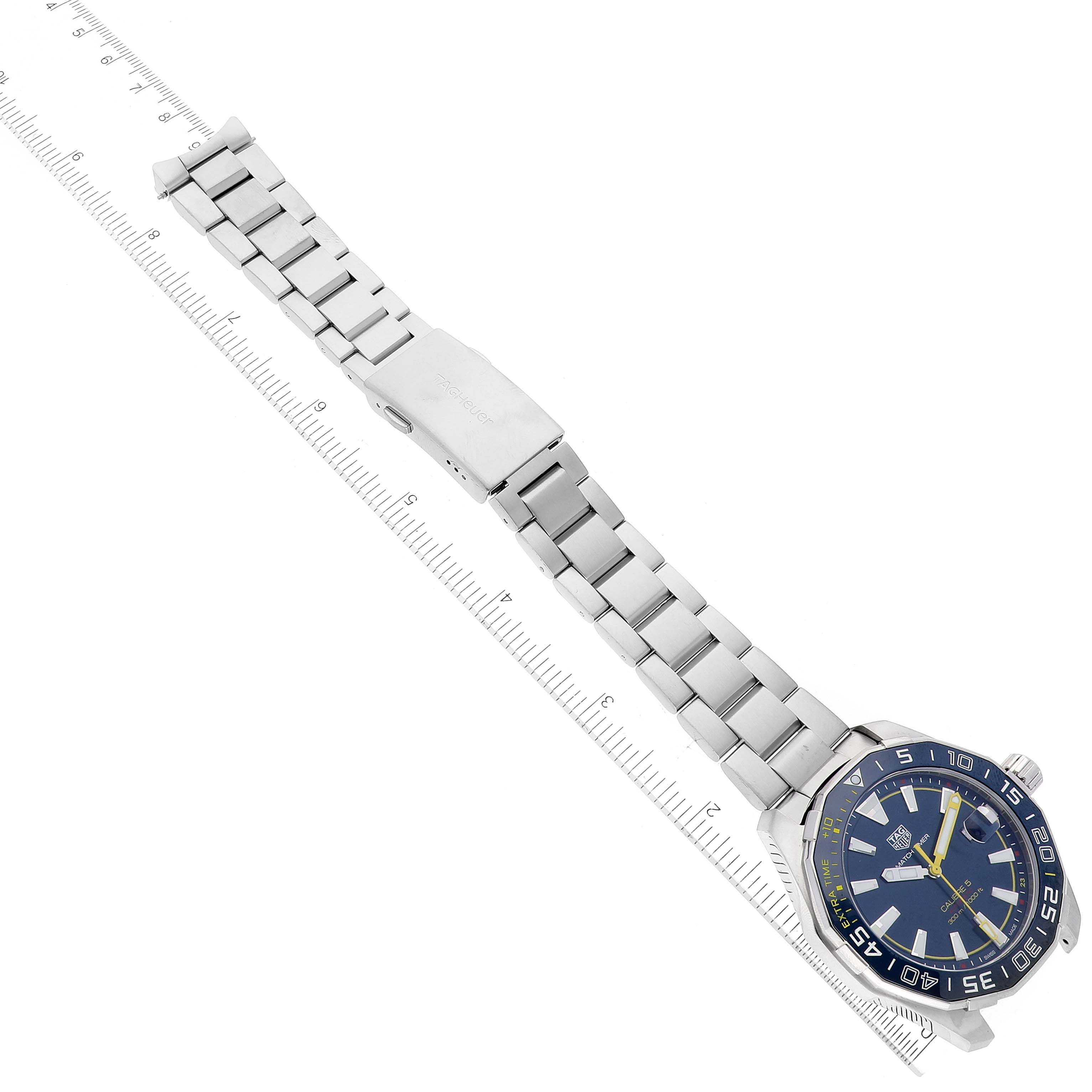 The image shows a Tag Heuer Aquaracer watch laid flat, displaying the dial, bezel, and metal bracelet with clasp.
