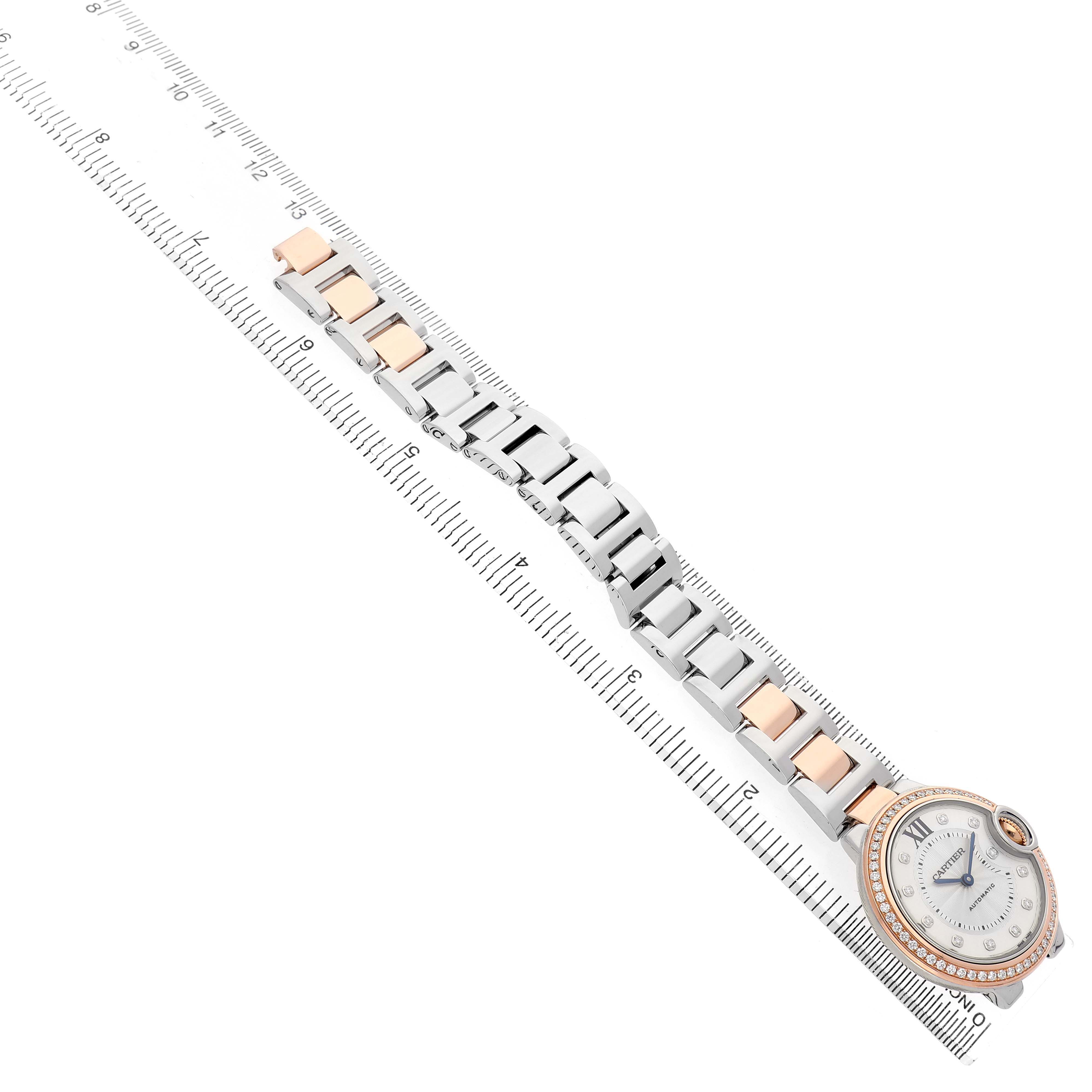 The image shows a Cartier Ballon Bleu WE902077 Women's Steel and Gold (two tone) Silver Dial watch face at a tilted angle, with the bracelet laid flat alongside a ruler.