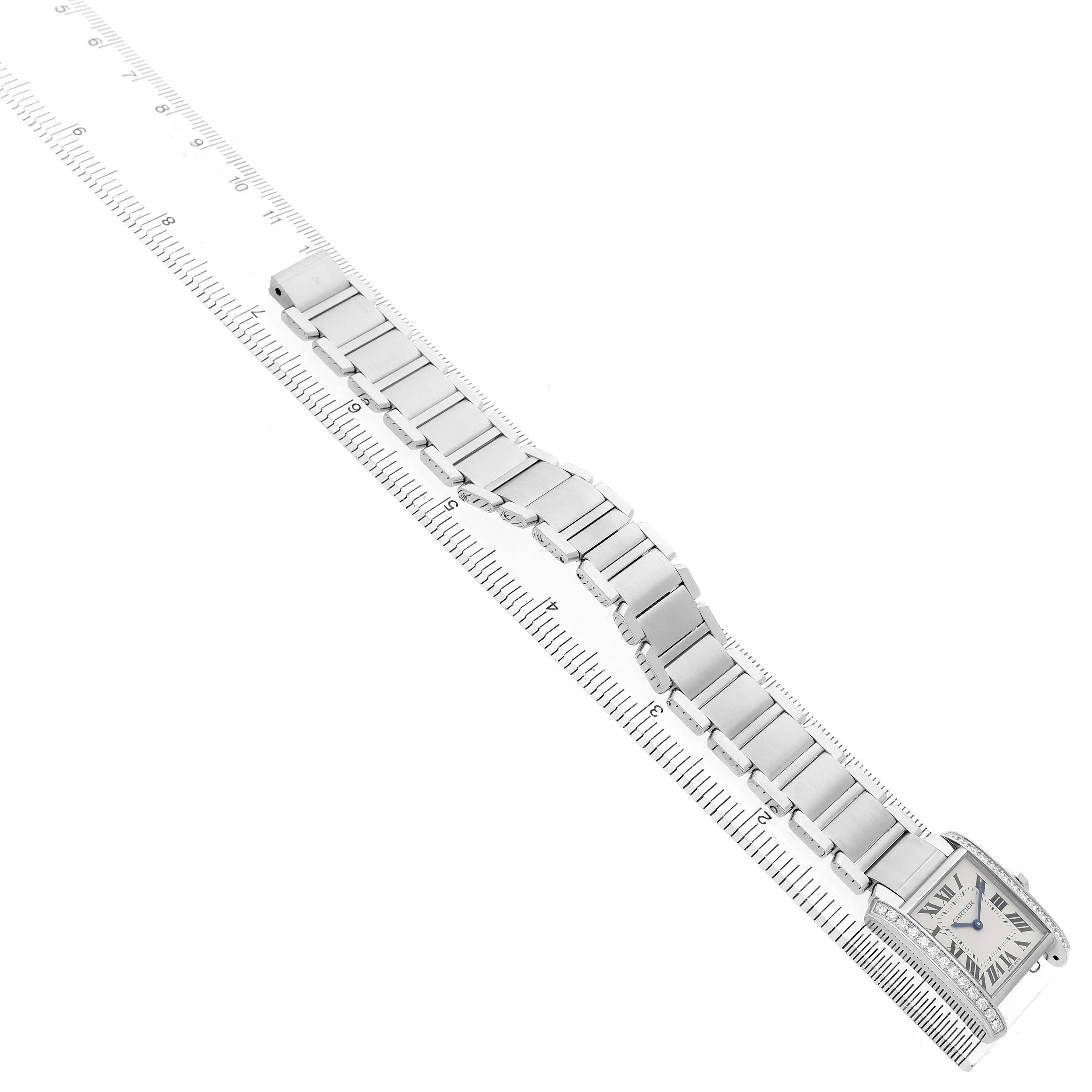 The Cartier Tank Française watch is shown in an angled view, highlighting its bracelet and rectangular face beside a ruler.