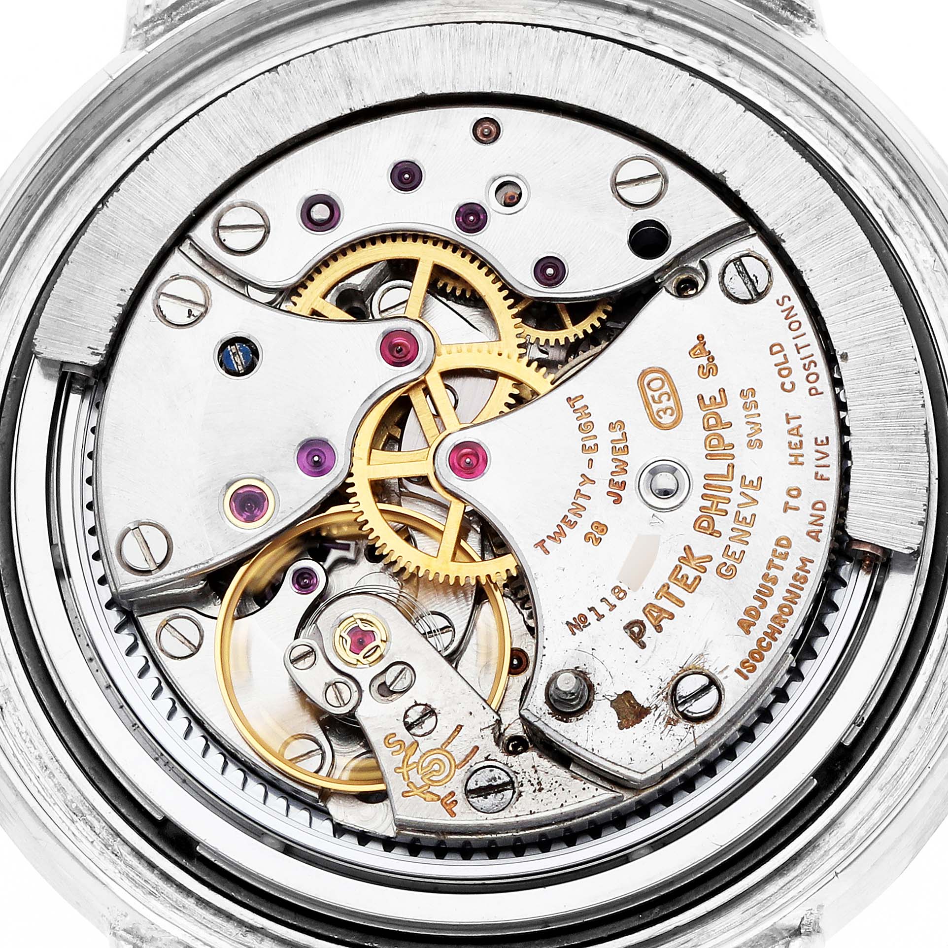 The image shows the intricate inner mechanism of a Vintage Patek Philippe watch from a top-down angle, highlighting gears and engravings.