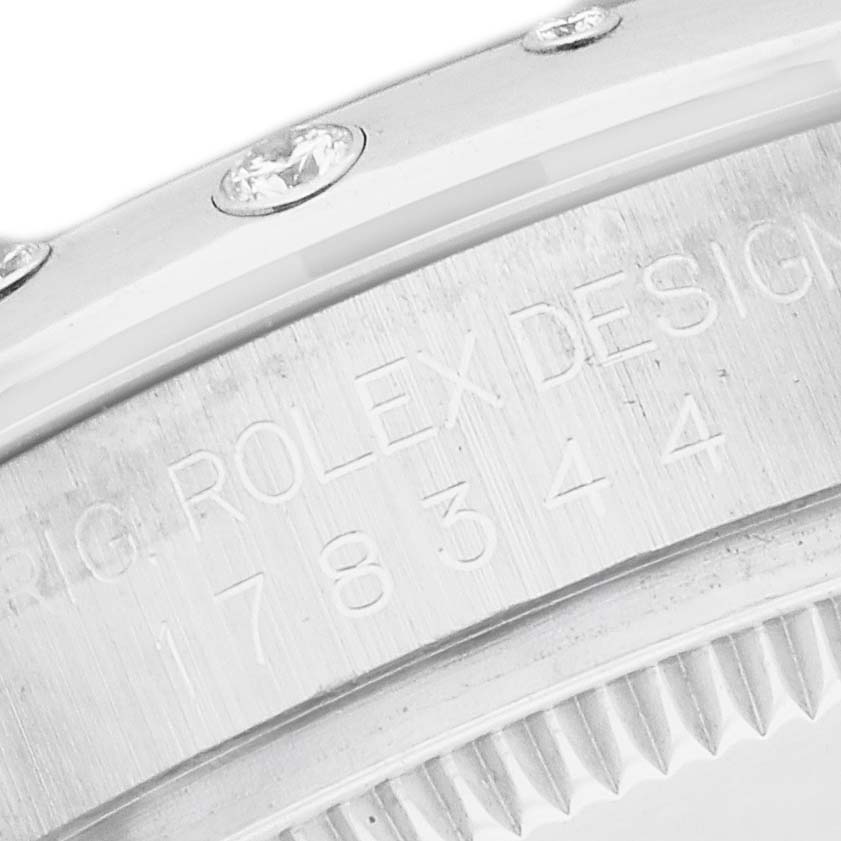 The image shows a close-up of a Rolex Mid-Size 178344 Women
s Stainless Steel Silver Dial watch bezel with engraved text and diamonds.