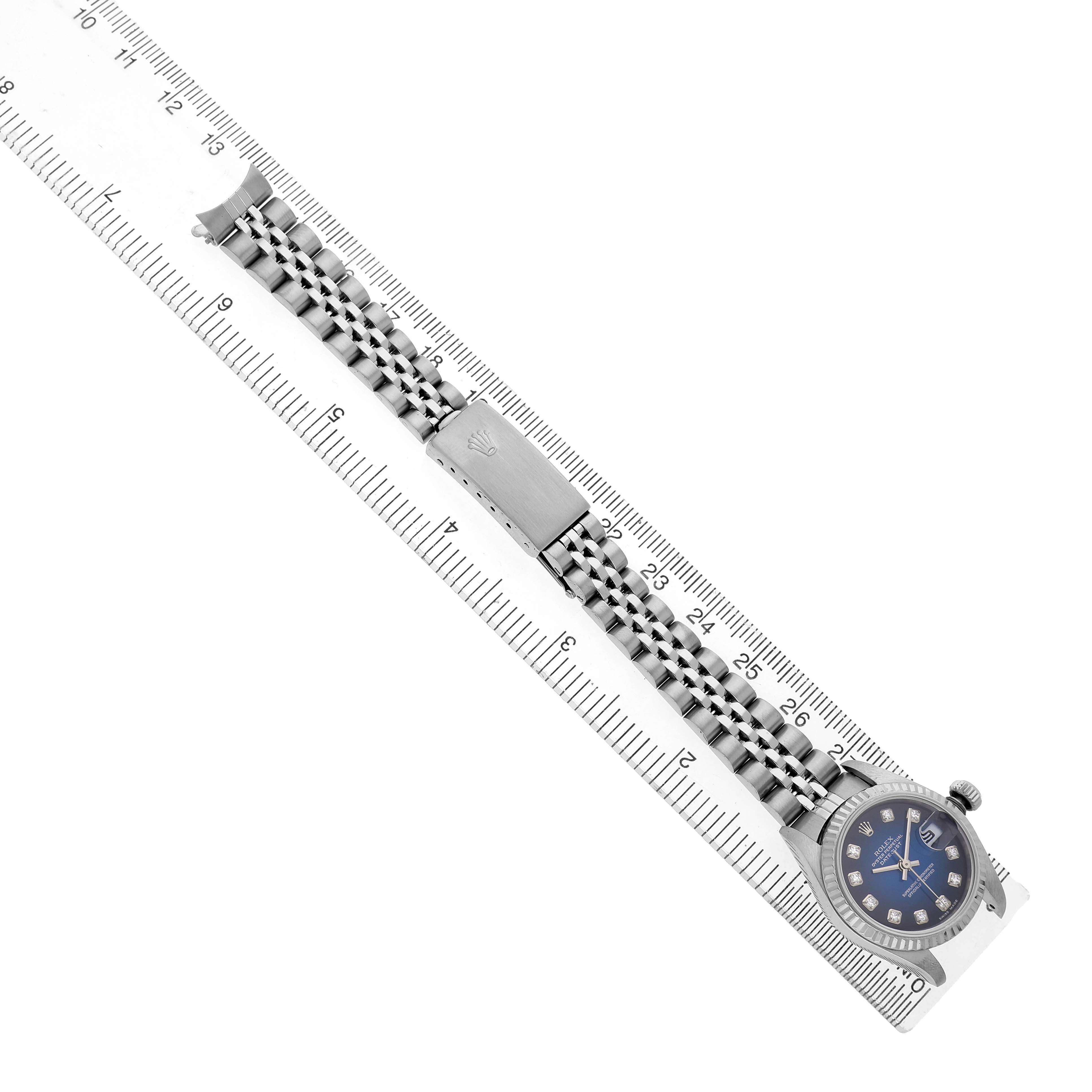 The Rolex Datejust 79174 Women's Stainless Steel Blue Dial is shown from a top-down angle, featuring the watch face, bracelet, and clasp aligned along a ruler.