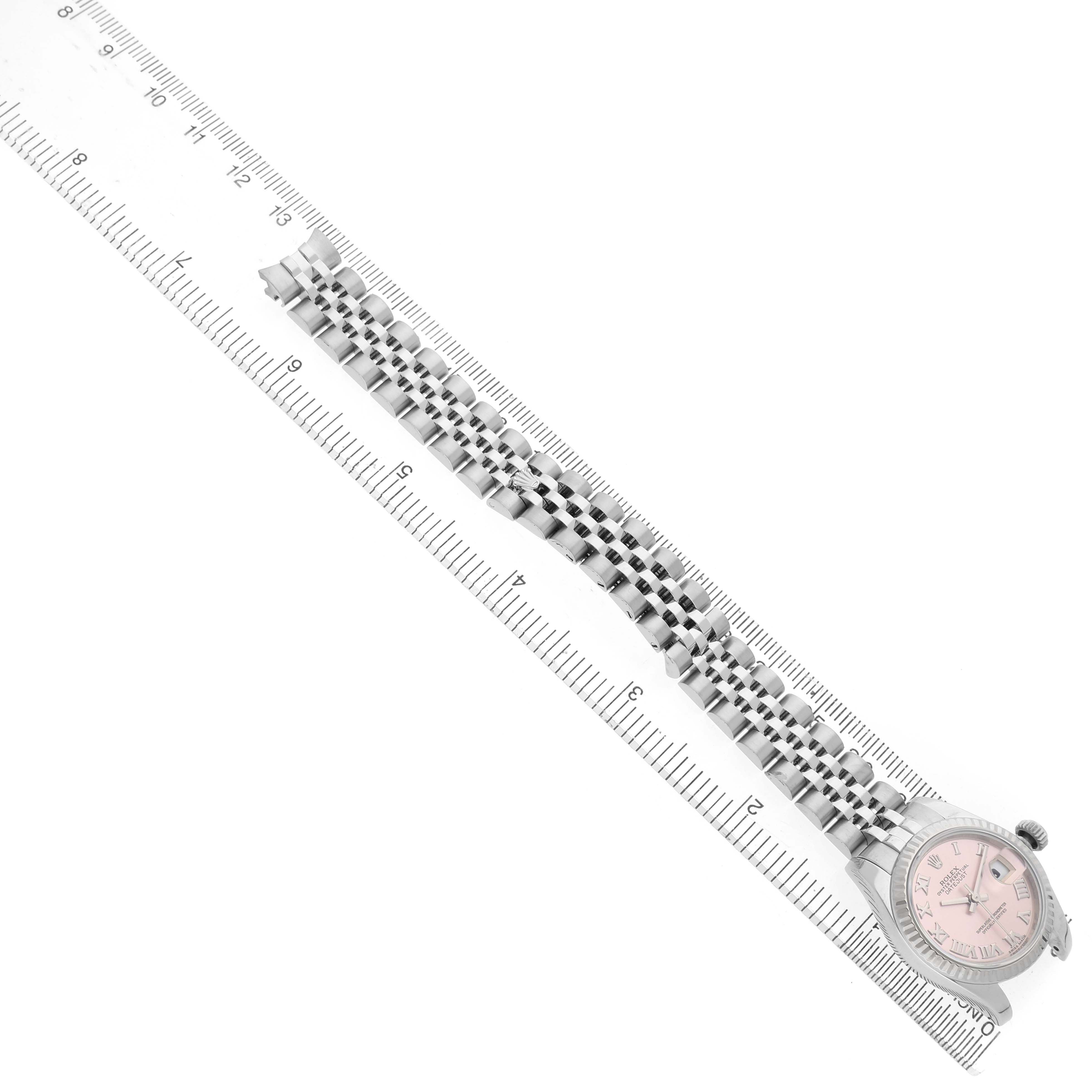 The image shows a Rolex Datejust 179174 Women's Stainless Steel Pink Dial watch face and bracelet from a top-down angle, alongside a ruler for scale.