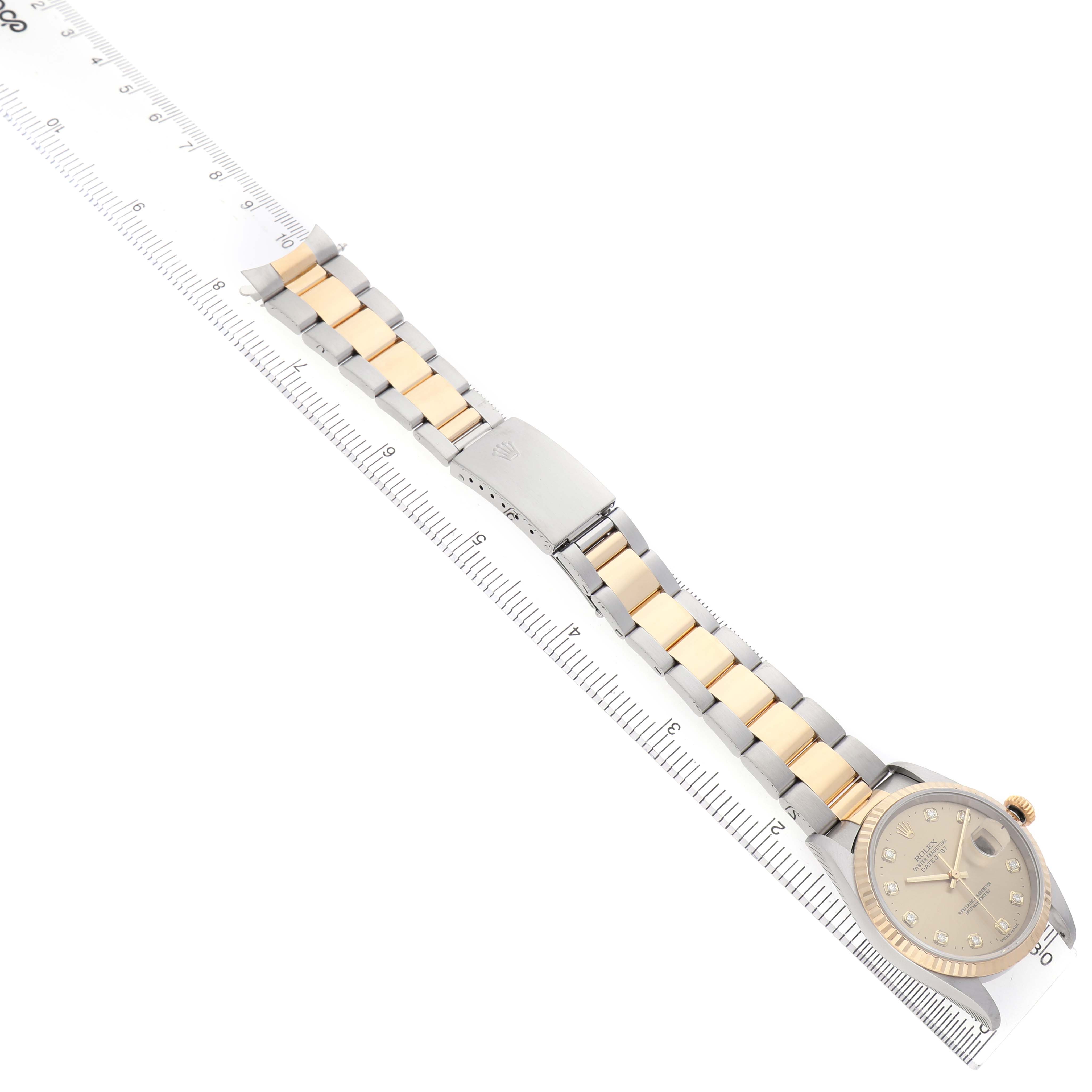 The Rolex Datejust 16233 Men's Stainless Steel Champagne Dial watch is displayed diagonally, showing the face, bracelet, and clasp fully extended alongside a ruler.