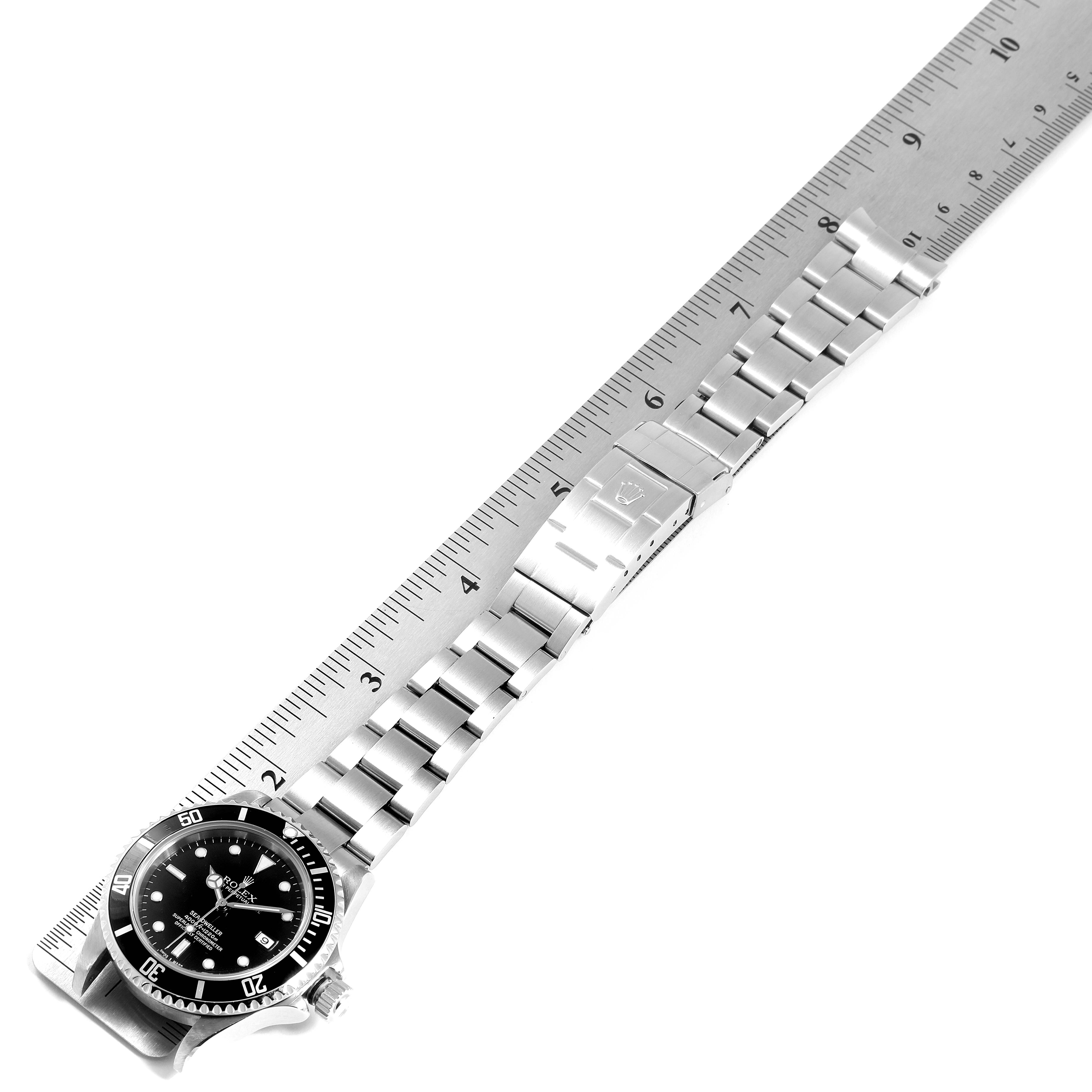The image shows a full view from above of the Rolex Submariner 16600 Men
s Stainless Steel Black Dial 16600 Men
s Stainless Steel Black Dial watch with its metal bracelet aligned next to a ruler.
