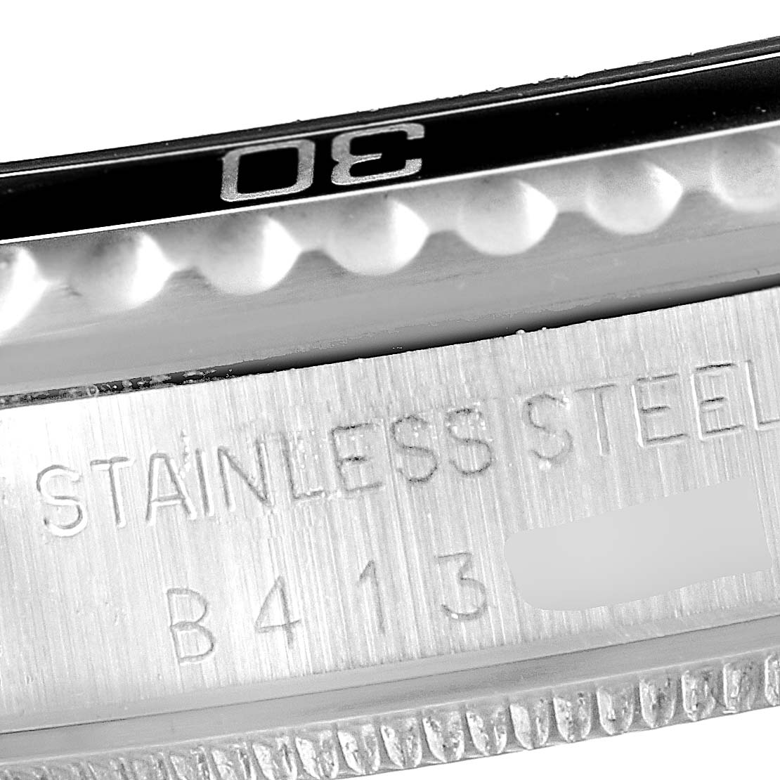 Close-up image of a Tudor Submariner 75090 Men
s Stainless Steel Black Dial 75090 Men
s Stainless Steel Black Dial watch showing parts of the bezel and caseback engraving.