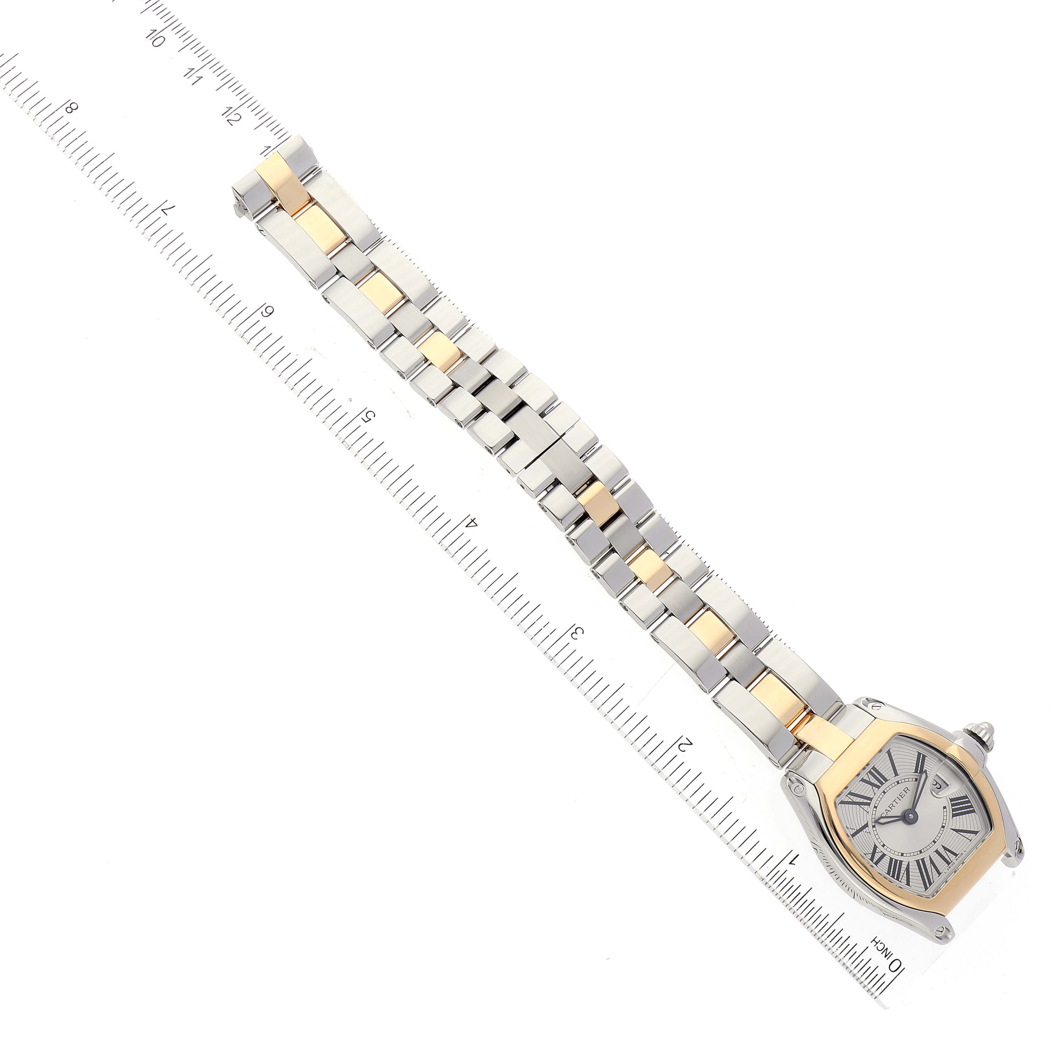 The image shows a top view of the Cartier Roadster W62026Y4 Women
s Steel and Gold (two tone) Silver Dial W62026Y4 Women
s Steel and Gold (two tone) Silver Dial model watch with a silver and gold-toned bracelet next to a ruler.