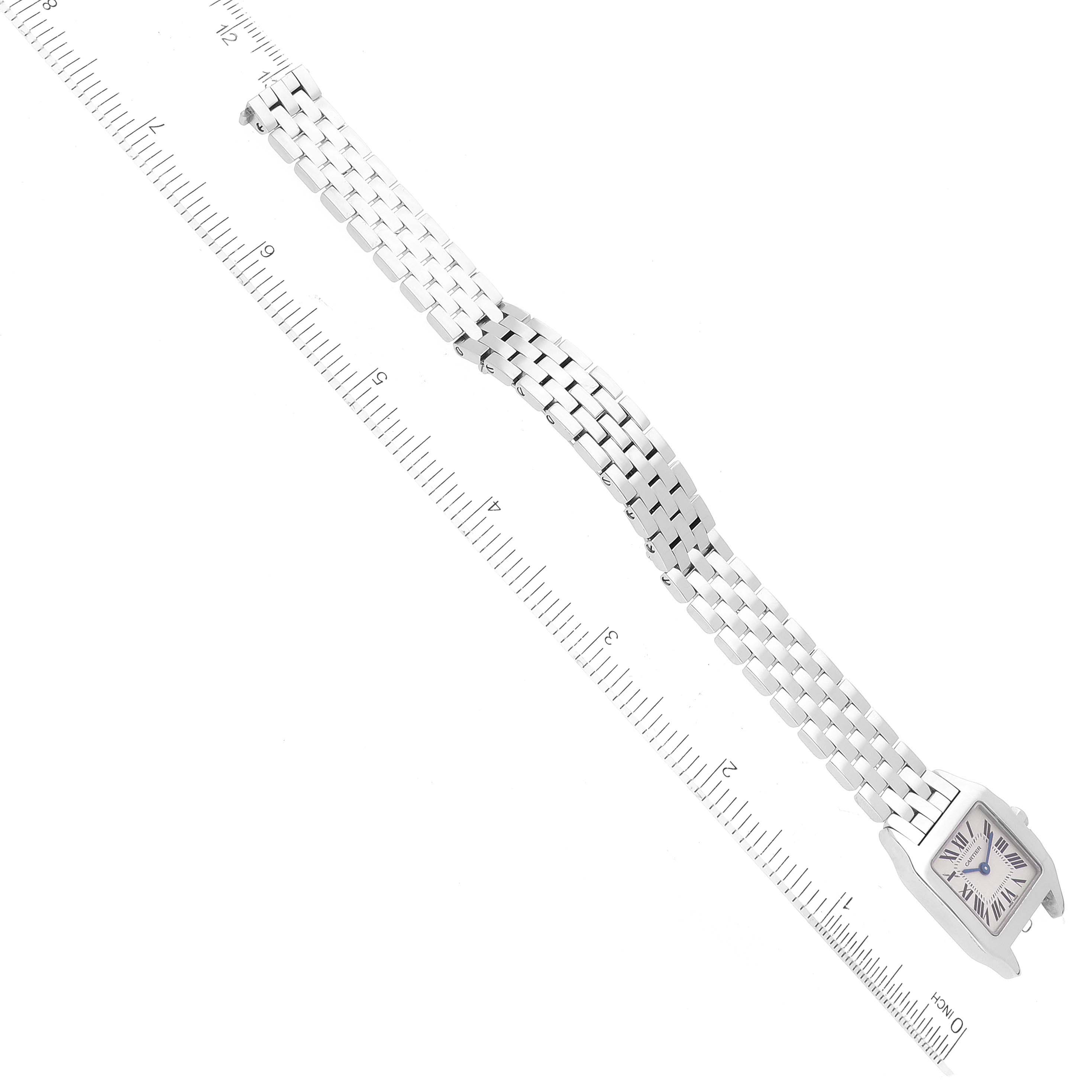 The image shows the front view of a Cartier Santos Demoiselle W25064Z5 Women
s Stainless Steel Silver Dial W25064Z5 Women
s Stainless Steel Silver Dial watch, including its face and metal bracelet, with a ruler for scale.