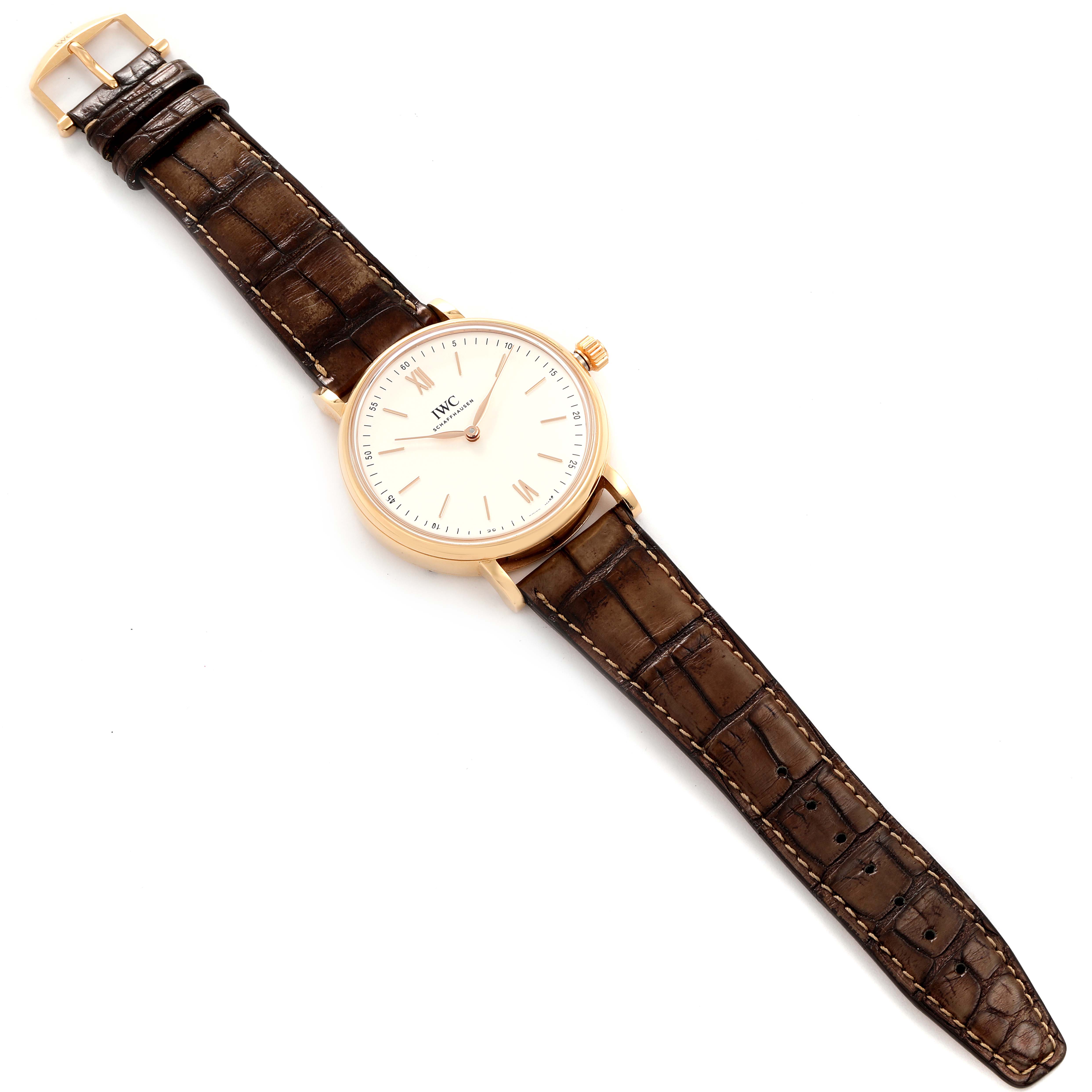 The IWC Portofino IW511101 Men's Rose Gold Silver Dial IW511101 Men's Rose Gold Silver Dial watch is shown from a top-down angle, displaying its face, brown leather strap, and gold case.