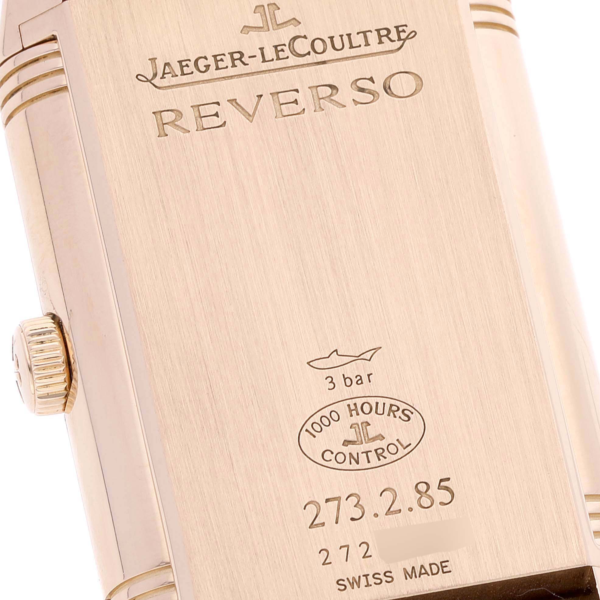 The image shows the case back of a Jaeger-LeCoultre Reverso watch, including the crown and various engravings.