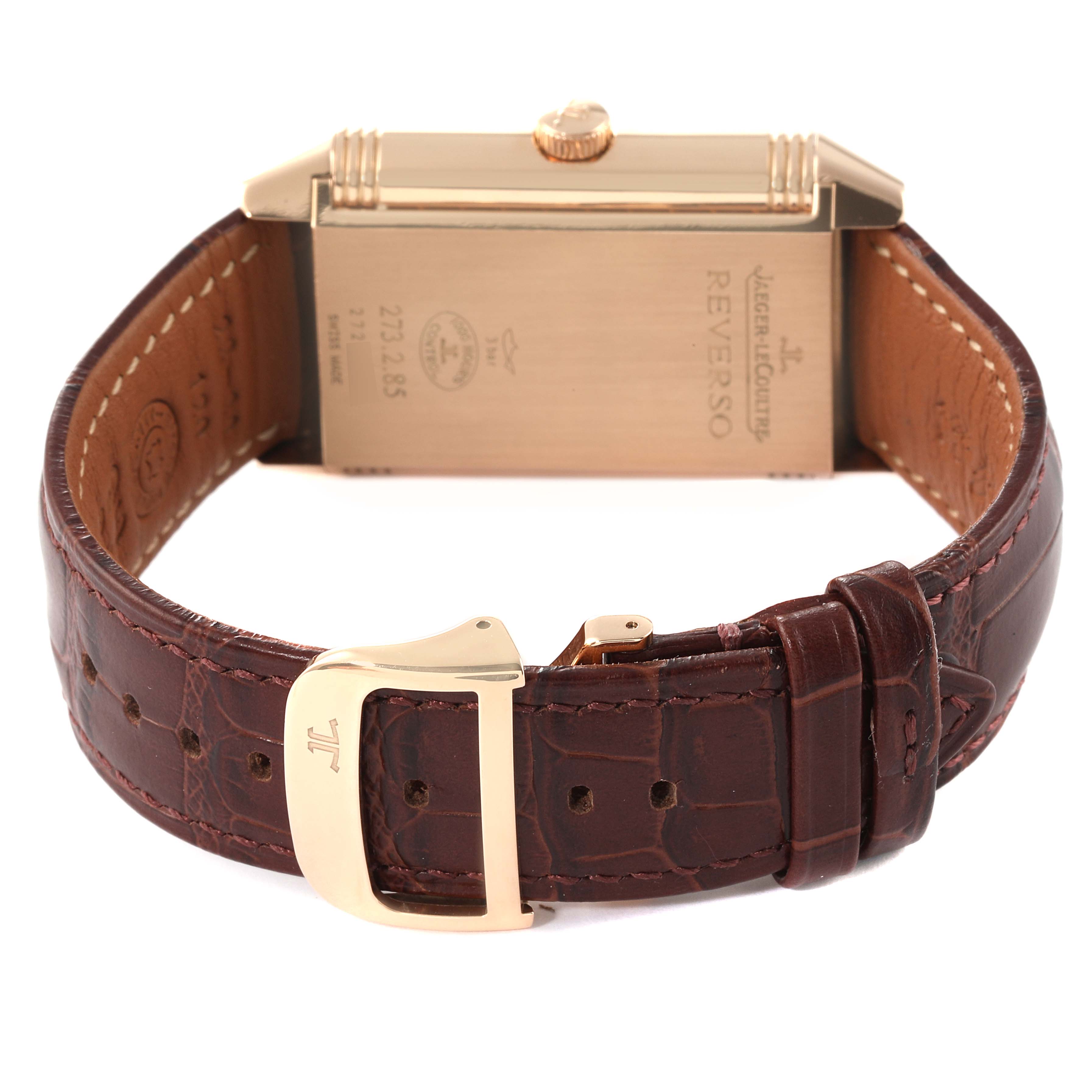 The image shows the back of a Jaeger-LeCoultre Reverso watch, highlighting its case, crown, and brown leather strap with a buckle.