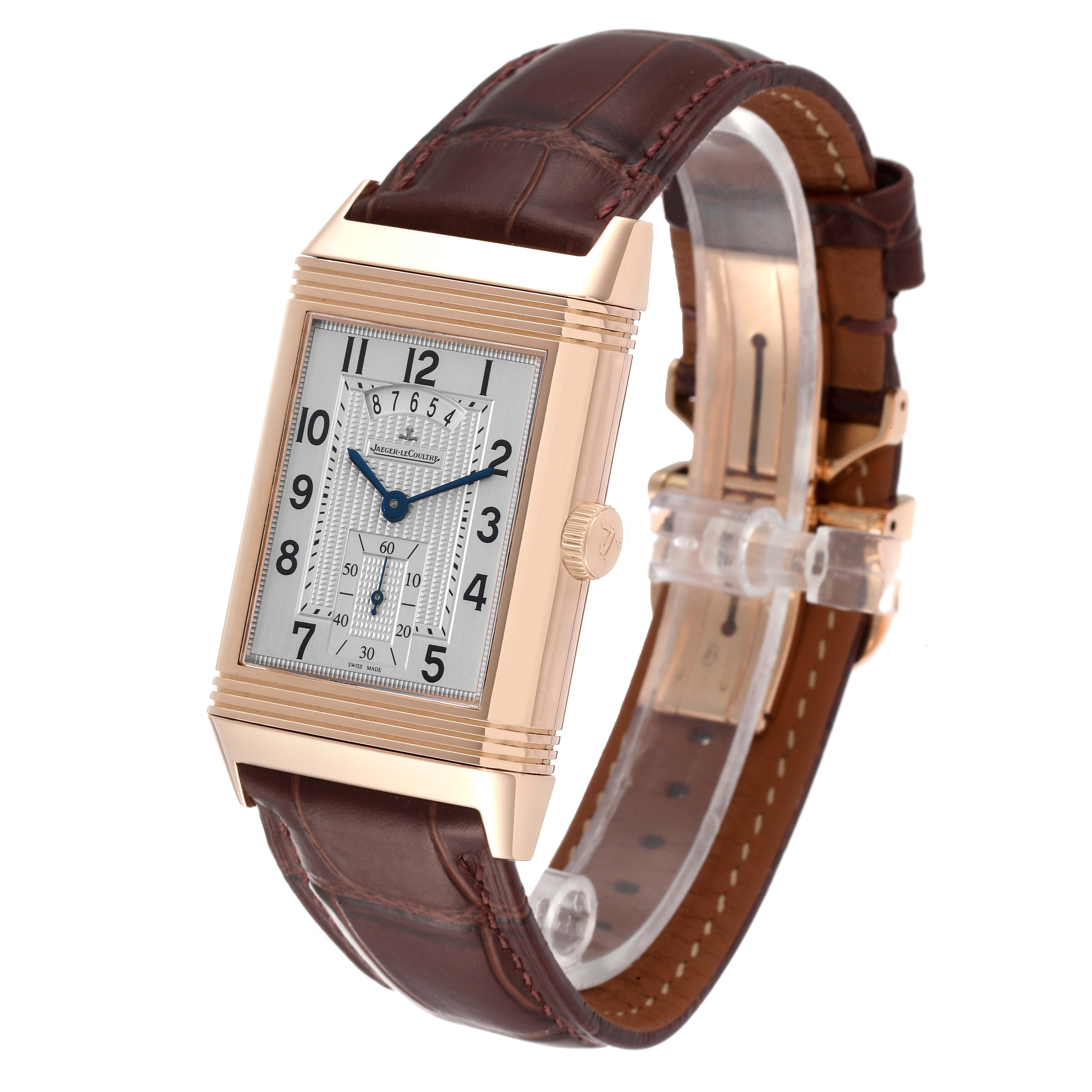 The Jaeger-LeCoultre Reverso watch is shown at an angled side view, featuring its rectangular case, leather strap, and dial.