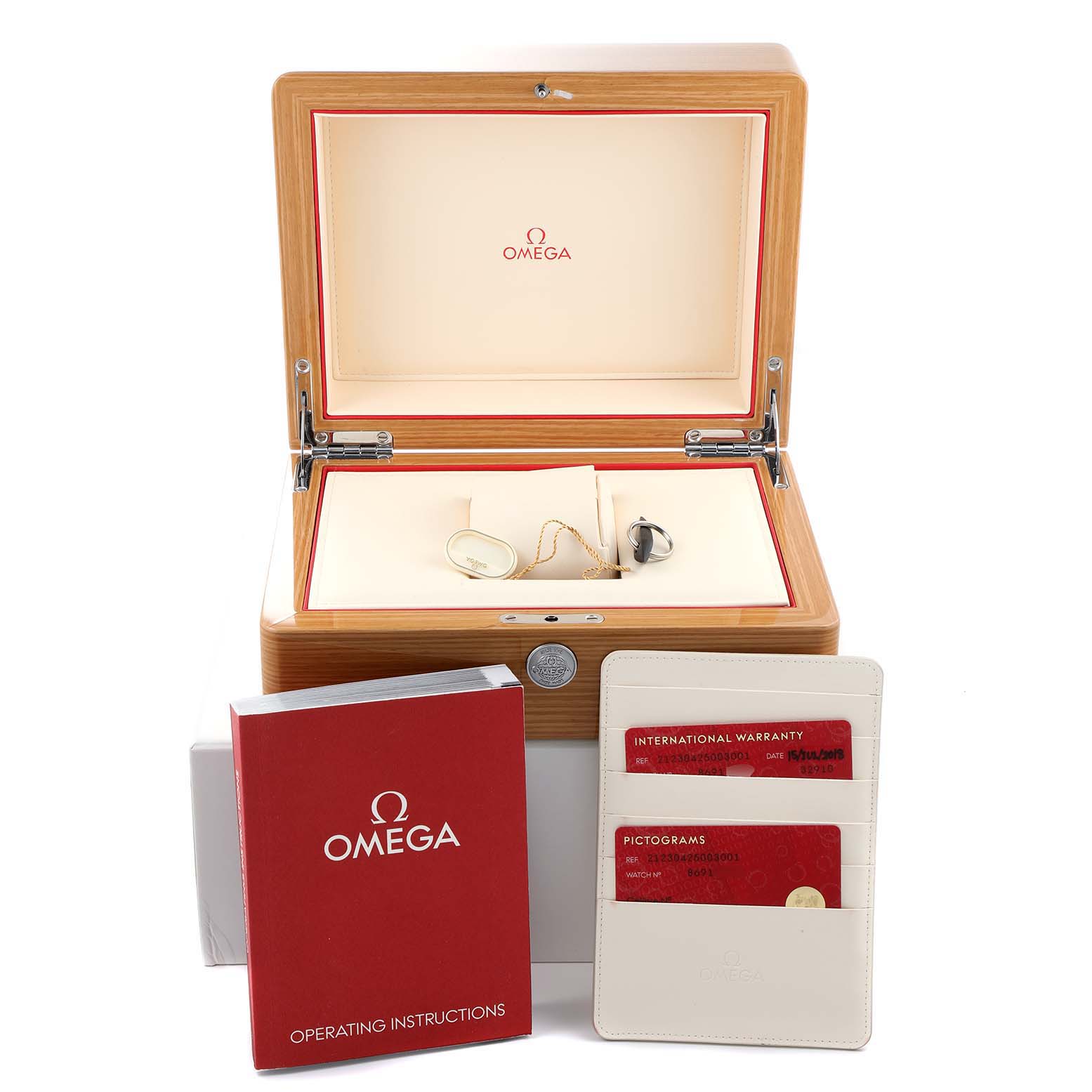 The image shows an Omega watch box, operating instructions, warranty cards, and some watch accessories for the Seamaster model.