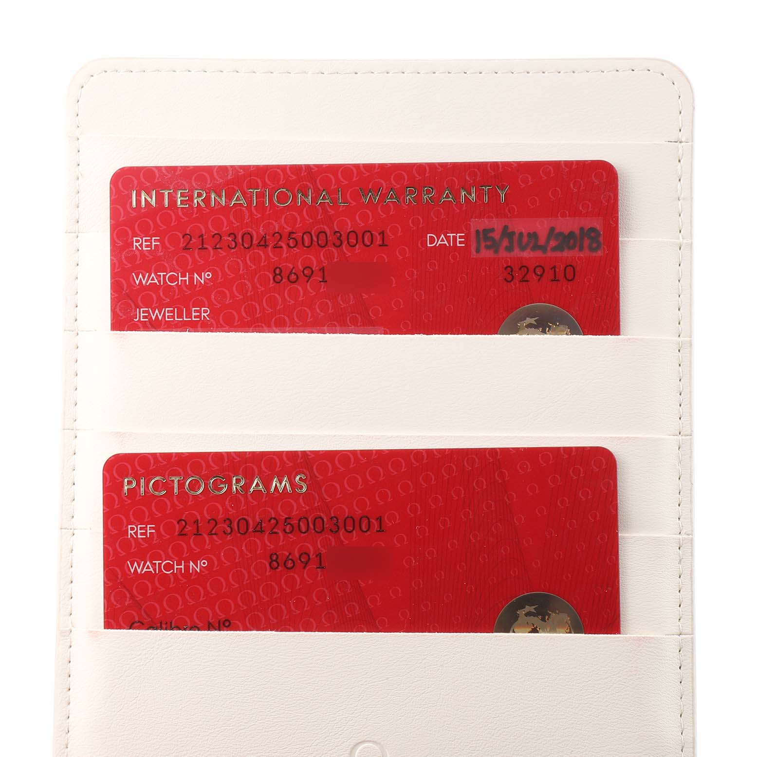 The image shows a close-up of international warranty and pictogram cards for an Omega Seamaster 212.30.42.50.03.001 Men's Stainless Steel Blue Dial 212.30.42.50.03.001 Men's Stainless Steel Blue Dial watch in a white holder.