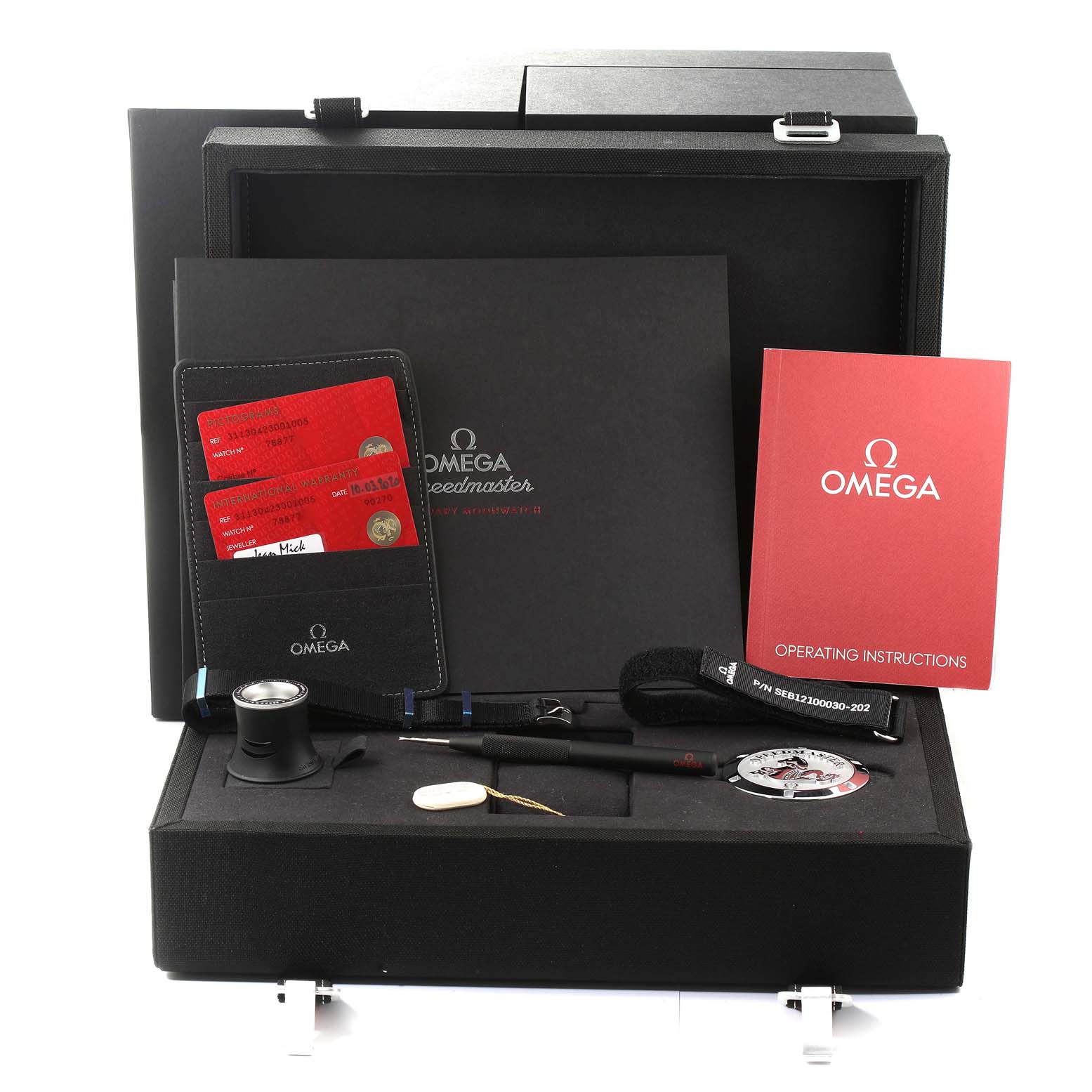 The image shows the packaging and accessories for the Omega Speedmaster 311.30.42.30.01.005 Men's Stainless Steel Black Dial 311.30.42.30.01.005 Men's Stainless Steel Black Dial, including warranty cards, operating instructions, and a loupe.