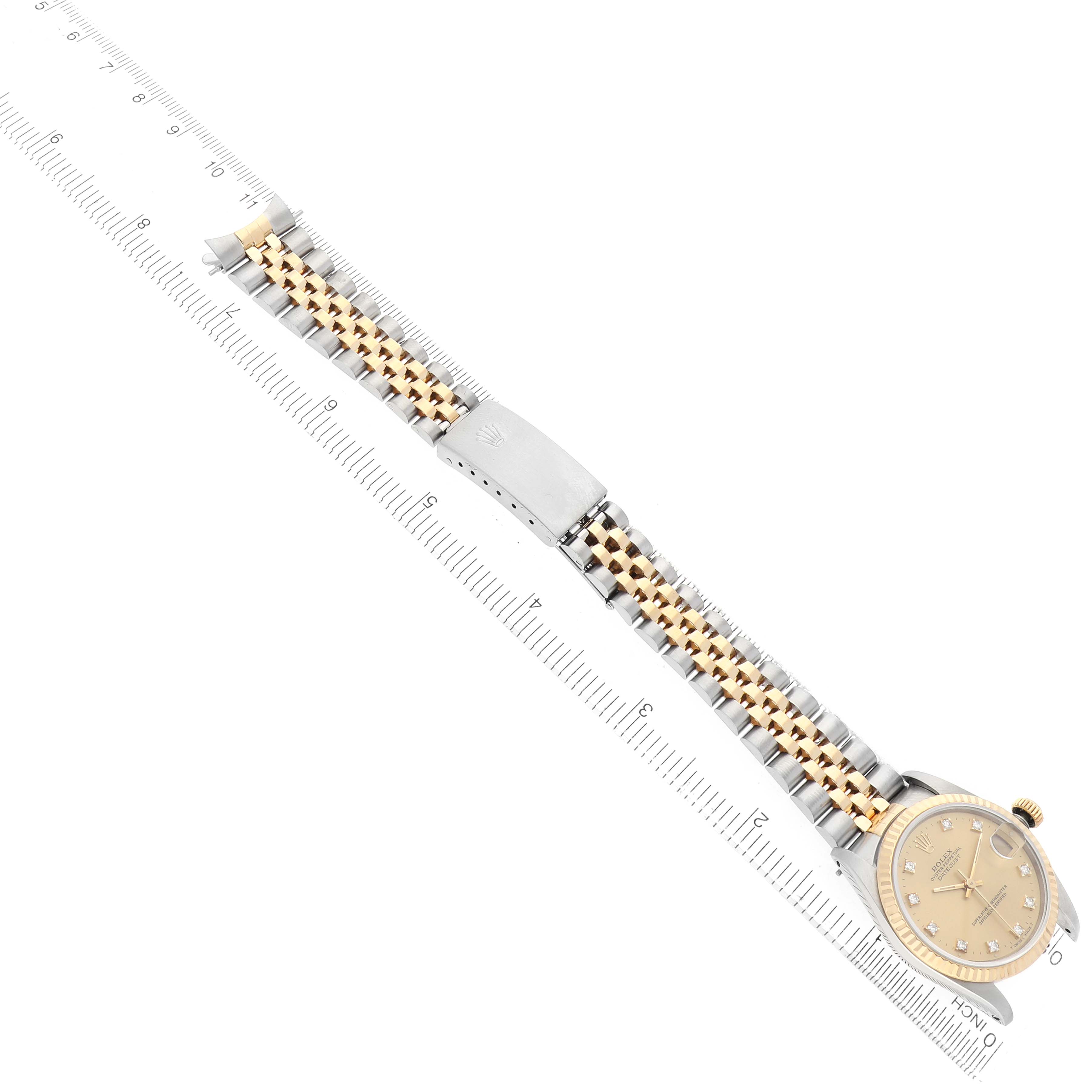The Rolex Datejust 68273 Women's Steel and Gold (two tone) Champagne Dial watch is shown from an overhead angle, displaying the full bracelet and face with a ruler alongside.