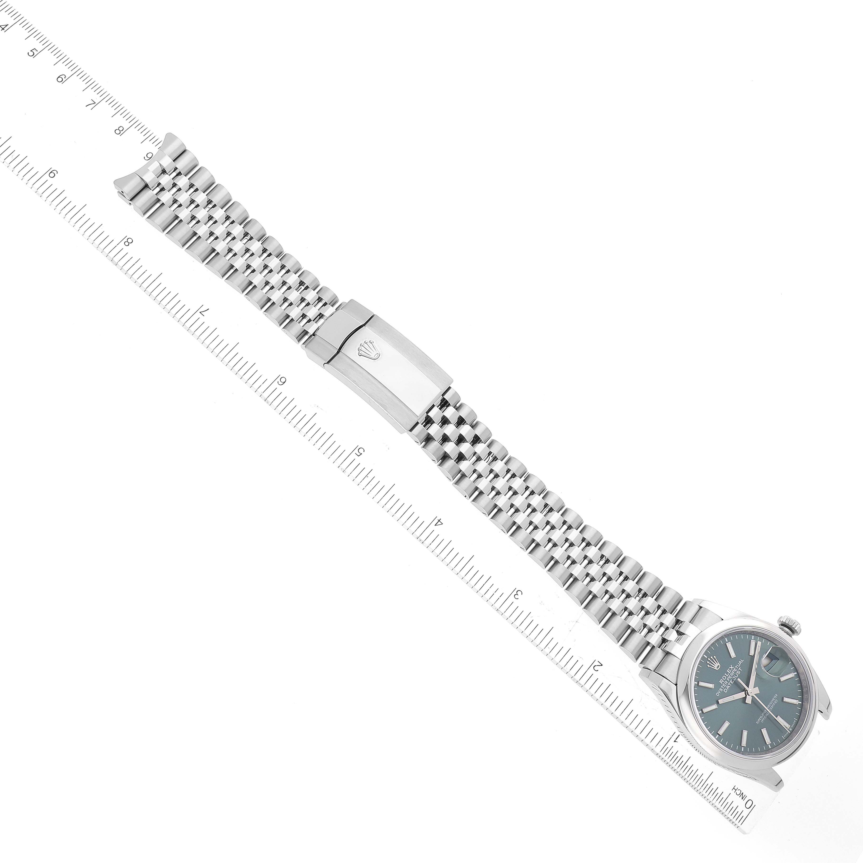 The image shows an aerial view of a Rolex Datejust 126200 Men's Stainless Steel Green Dial 126200 Men's Stainless Steel Green Dial watch, including its face, crown, and full bracelet.