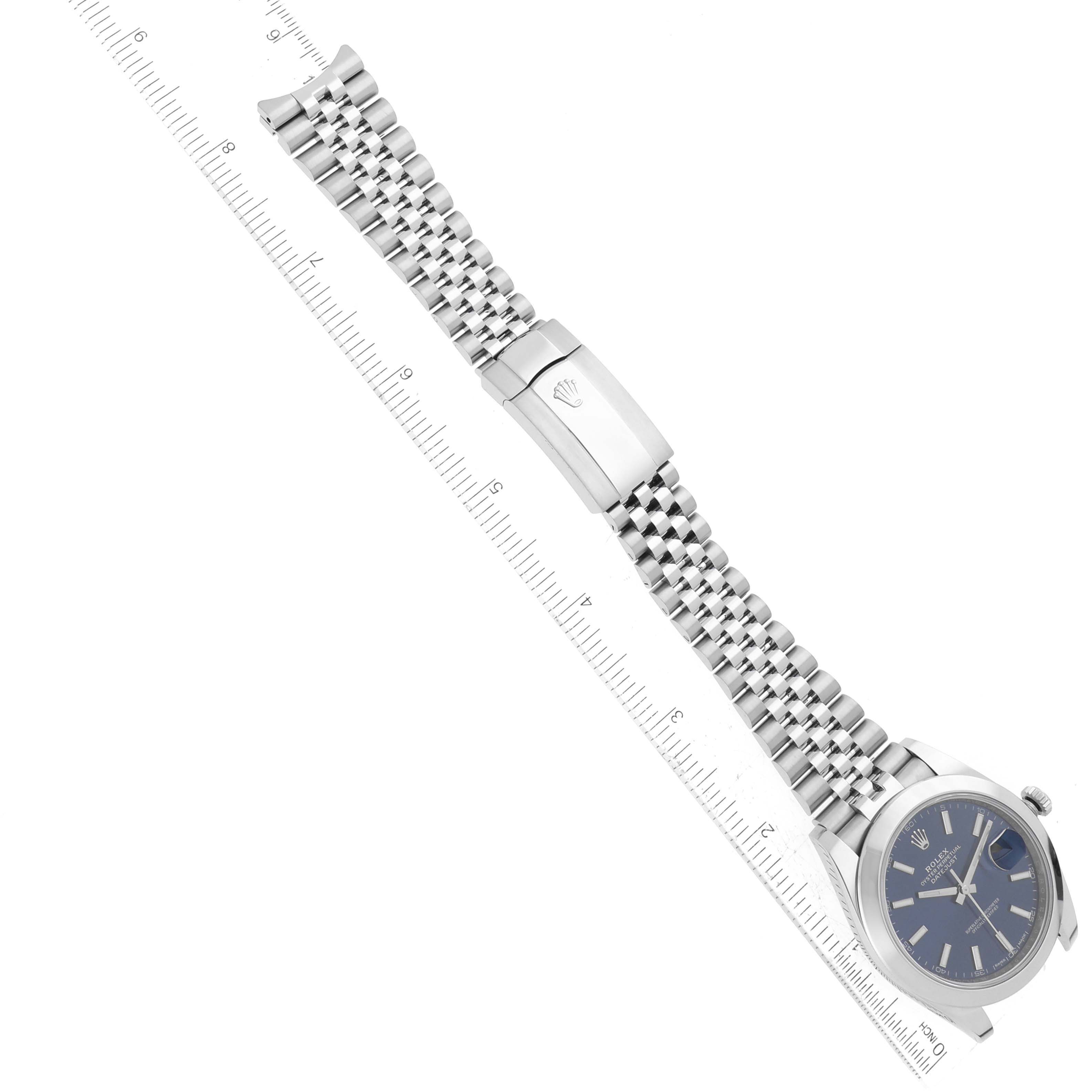 This image shows a Rolex Datejust 41 126300 Men
s Stainless Steel Blue Dial 126300 Men
s Stainless Steel Blue Dial watch laid flat, with a full view of the bracelet, clasp, and dial alongside a ruler for scale.