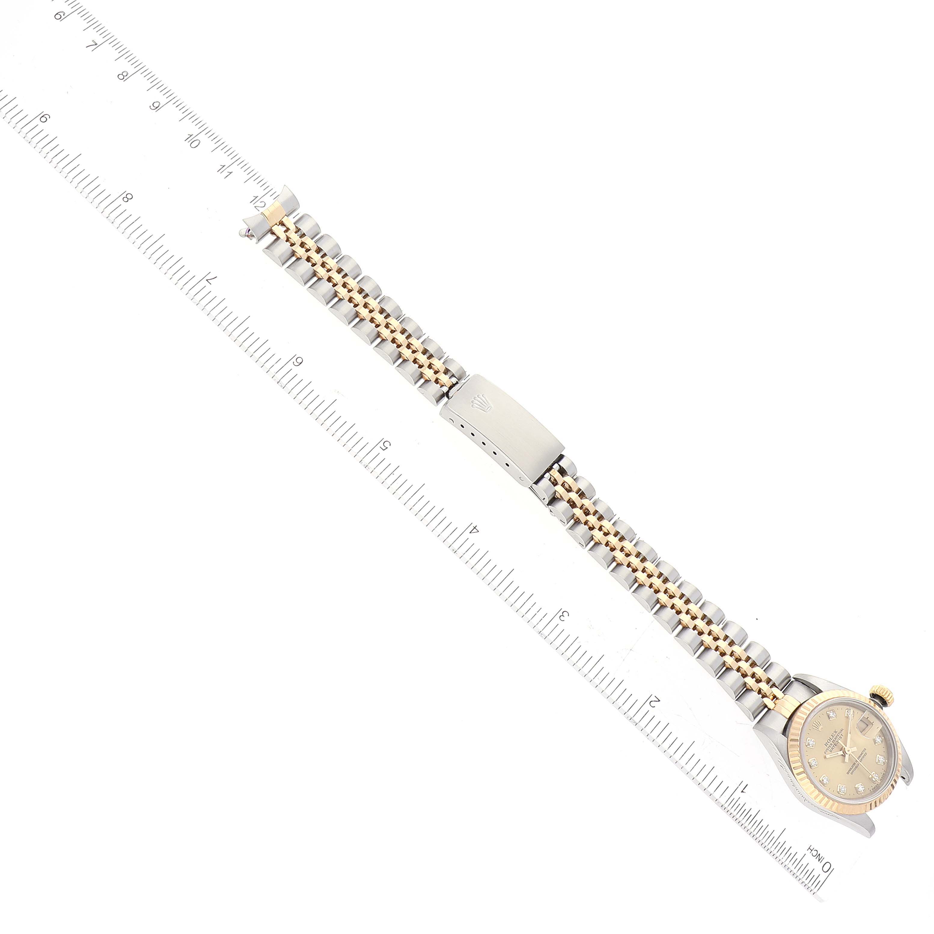 The image shows the Rolex Datejust 69173 Women's Steel and Gold (two tone) Champagne Dial 69173 Women's Steel and Gold (two tone) Champagne Dial watch laid flat, highlighting its face, bracelet, and clasp with a ruler for scale.