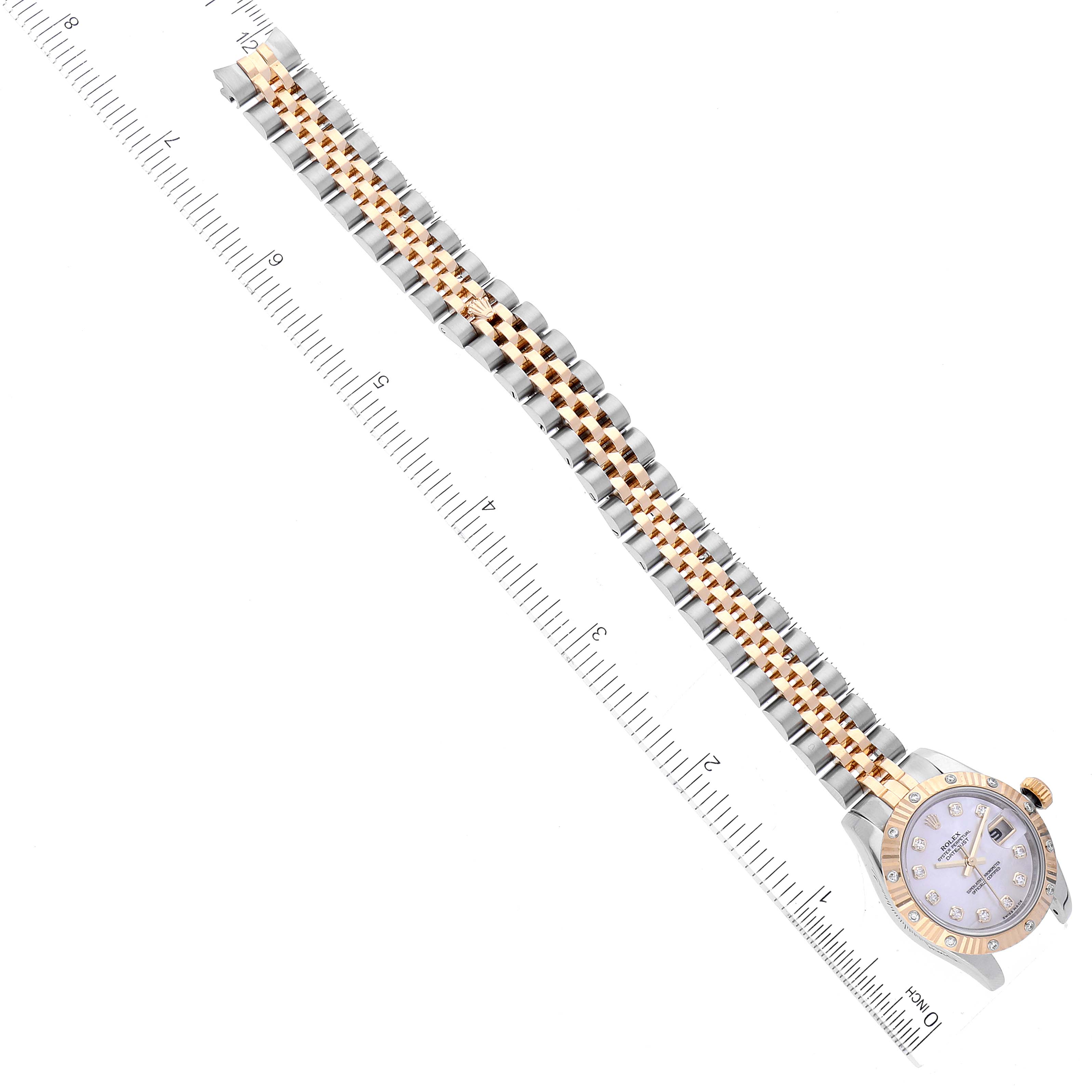The image shows a Rolex Datejust 179313 Women
s Steel and Gold (two tone) Mother of Pearl Dial 179313 Women
s Steel and Gold (two tone) Mother of Pearl Dial watch placed flat with its bracelet in full view alongside a ruler for scale.