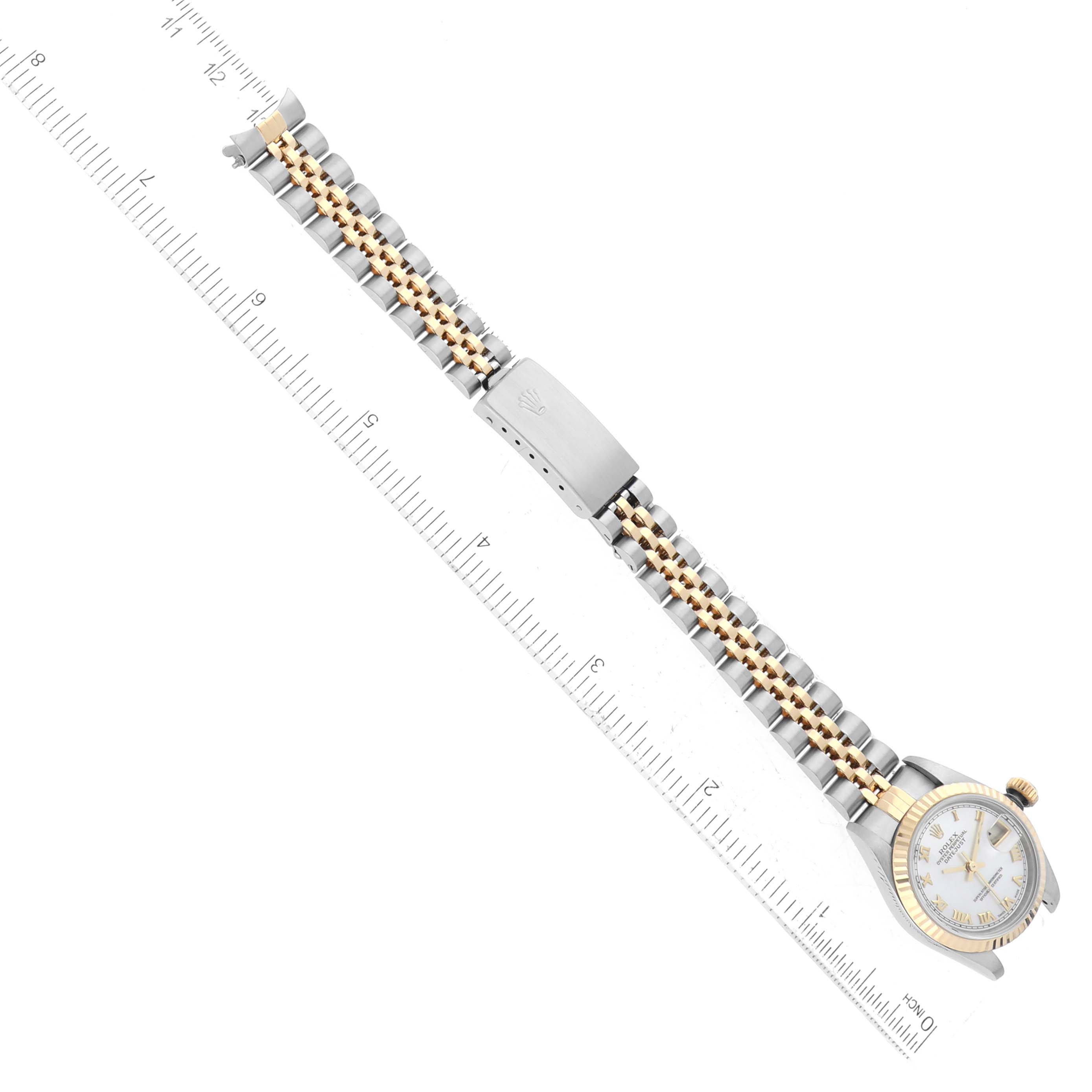 The image shows a Rolex Datejust 79173 Women
s Steel and Gold (two tone) Mother of Pearl Dial 79173 Women
s Steel and Gold (two tone) Mother of Pearl Dial watch lying flat, displaying the two-tone bracelet and face with a ruler beside it for scale.