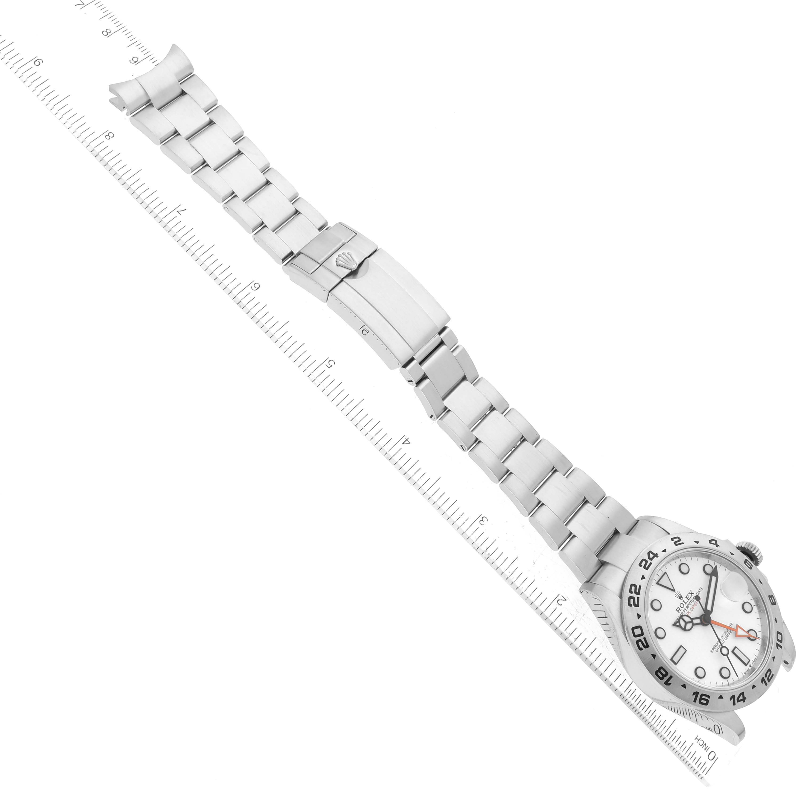 The Rolex Explorer 226570 Men's Stainless Steel White Dial 226570 Men's Stainless Steel White Dial watch is shown at an angle, displaying its face, bracelet, and clasp next to a measuring ruler.