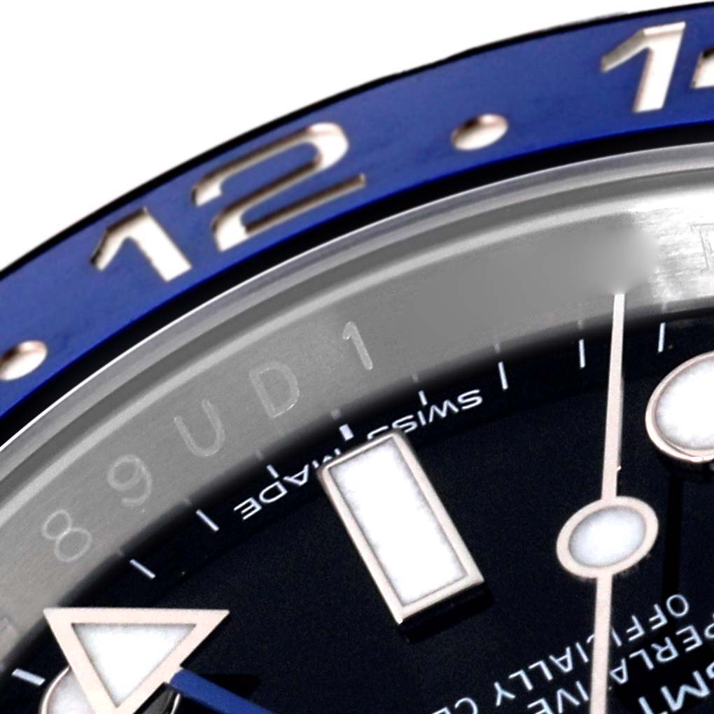 This close-up of the Rolex GMT-Master 116710BLNR Men's Stainless Steel Black Dial 116710BLNR Men's Stainless Steel Black Dial watch shows the bezel with the number 12 and part of the dial with luminous markers.