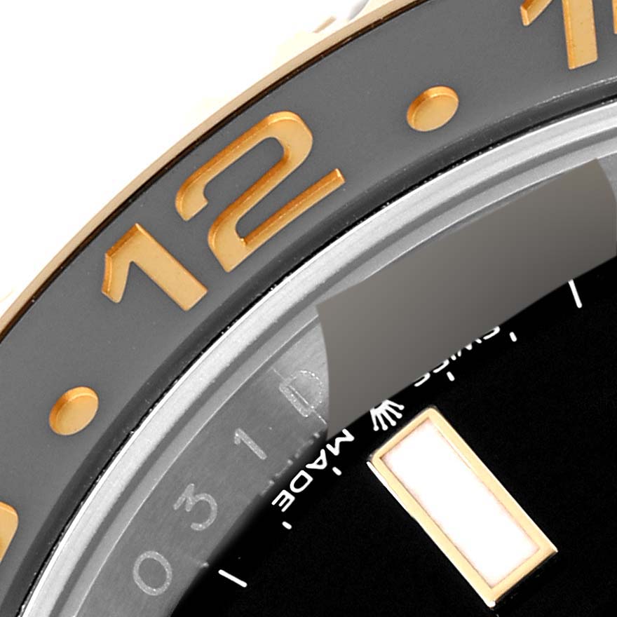 This close-up image of a Rolex GMT-Master 126713 Men's Steel and Gold (two tone) Black Dial 126713 Men's Steel and Gold (two tone) Black Dial watch showcases part of the bezel, dial, and indices.
