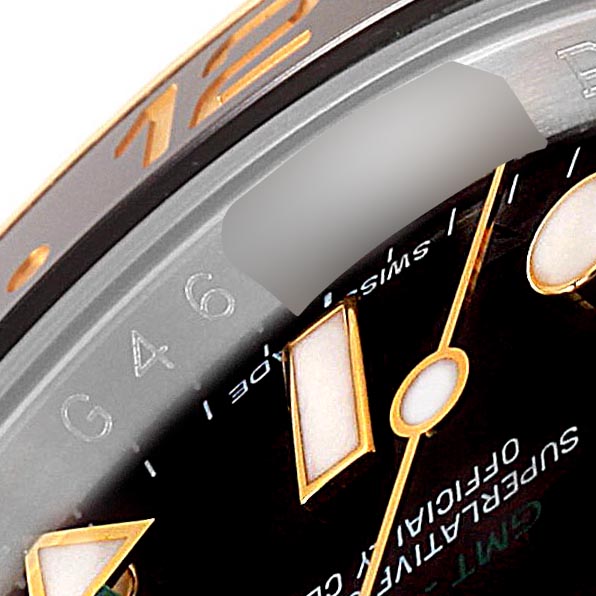 This close-up image shows the bezel, part of the dial, and the gold hour markers of the Rolex GMT-Master 116713 Men's Steel and Gold (two tone) Black Dial 116713 Men's Steel and Gold (two tone) Black Dial watch.