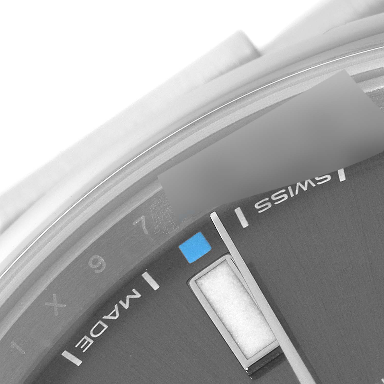 This is a close-up of the dial and hour markers of a Rolex Oyster Perpetual 114300 Men's Stainless Steel Grey Dial 114300 Men's Stainless Steel Grey Dial watch, showing part of the bezel and "SWISS MADE" text.