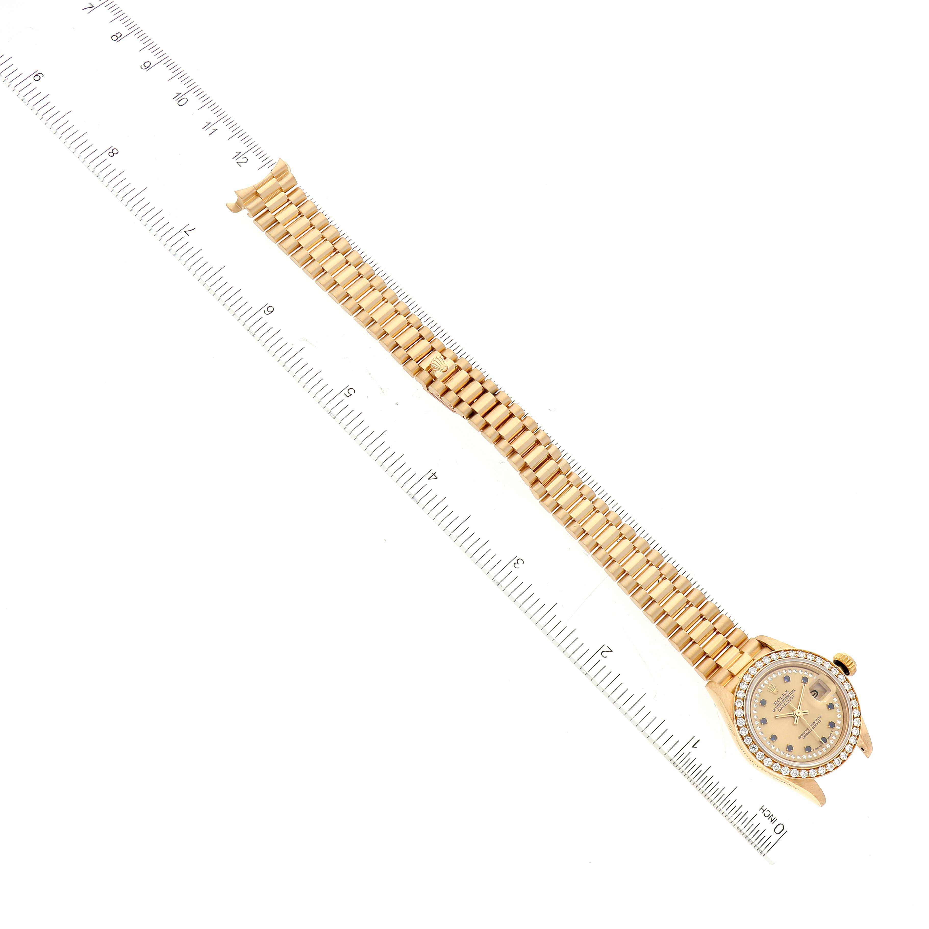 The Rolex President 69138 Women's Yellow Gold Champagne Dial 69138 Women's Yellow Gold Champagne Dial model watch is shown from a top-down angle, displaying the face, bezel, and full bracelet with a ruler for scale.