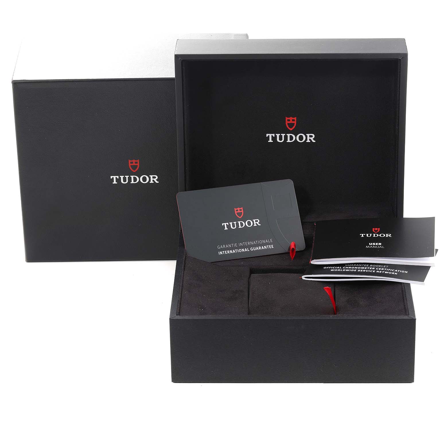 The Heritage Black Bay by Tudor is shown in its open box with warranty cards and user manuals visible.