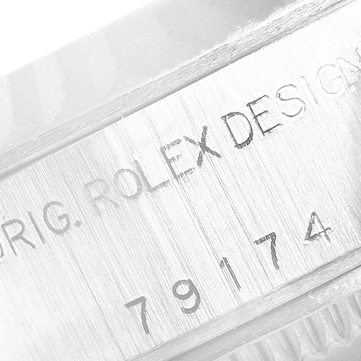 This close-up image shows the engraved serial number and "Rolex Design" text on the case of a Rolex Datejust 79174 Women's Stainless Steel Mother of Pearl Dial 79174 Women's Stainless Steel Mother of Pearl Dial watch.
