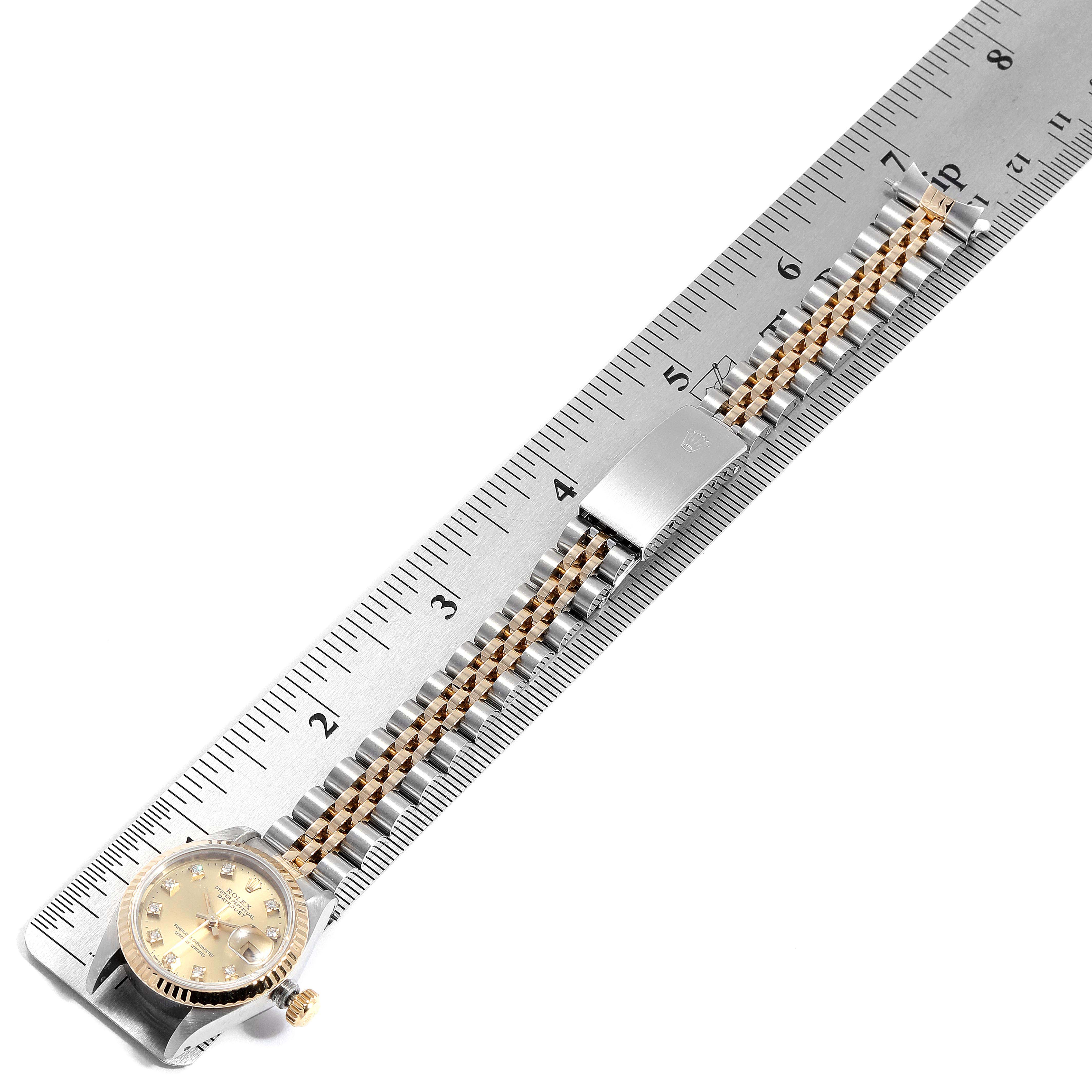 The image shows a Datejust model Rolex watch with its bracelet aligned alongside a metal ruler.