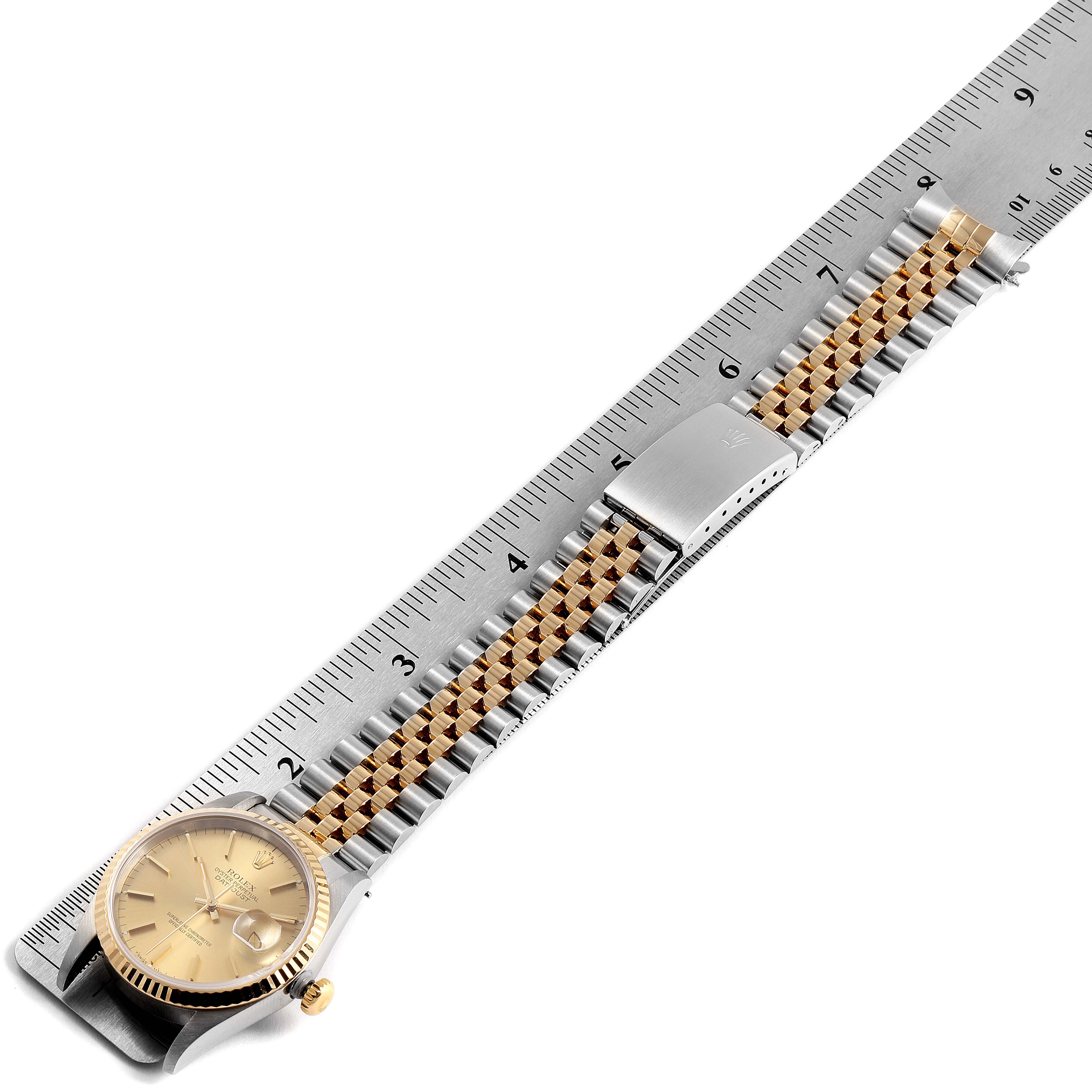 This image shows the Rolex Datejust 16233 Men's Steel and Gold (two tone) Champagne Dial 16233 Men's Steel and Gold (two tone) Champagne Dial watch, displaying its face, bezel, jubilee bracelet, and clasp against a measuring ruler.
