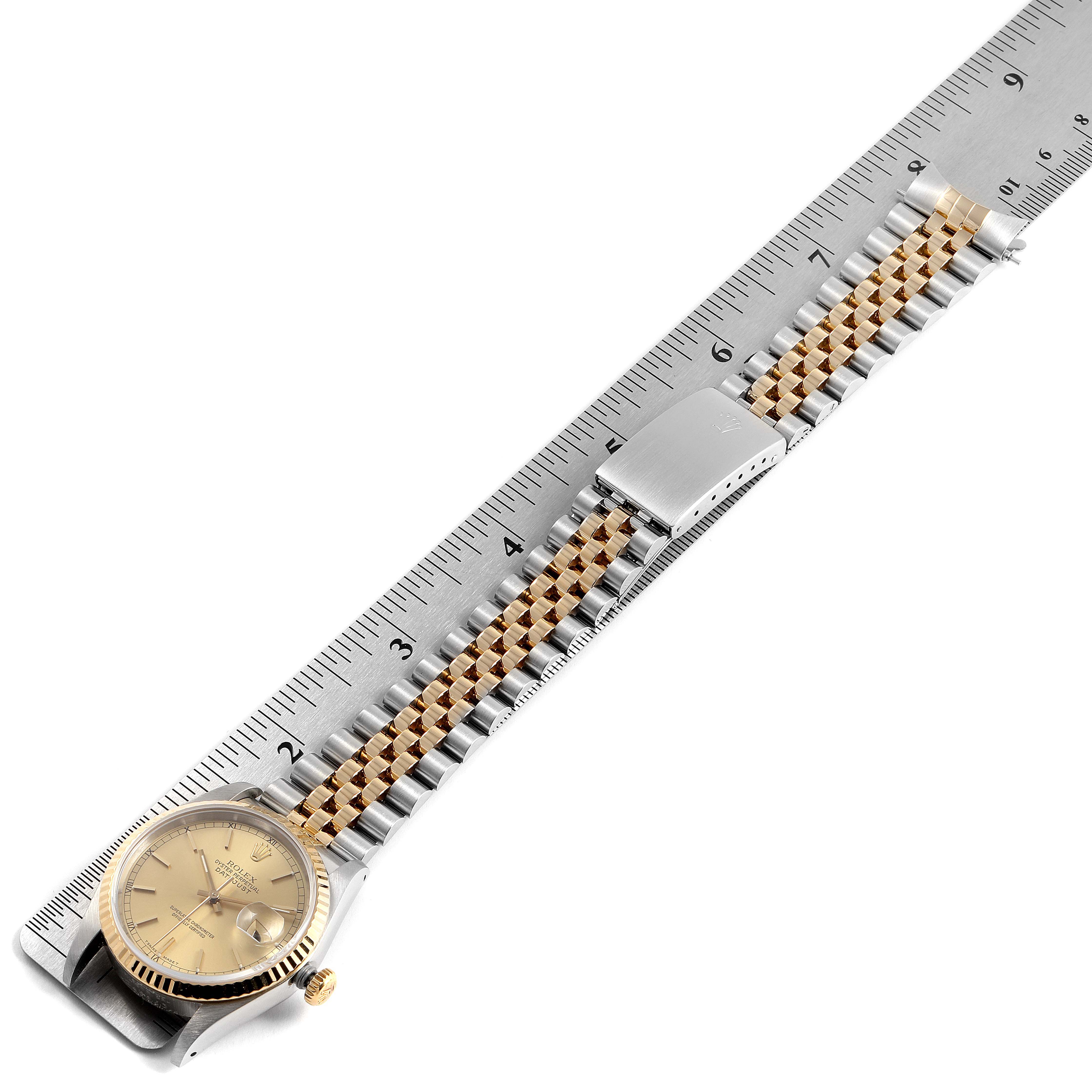 The image shows a Rolex Datejust 16233 Men's Steel and Gold (two tone) Champagne Dial 16233 Men's Steel and Gold (two tone) Champagne Dial watch laid flat alongside a ruler, highlighting the entire watch, including its band and clasp.