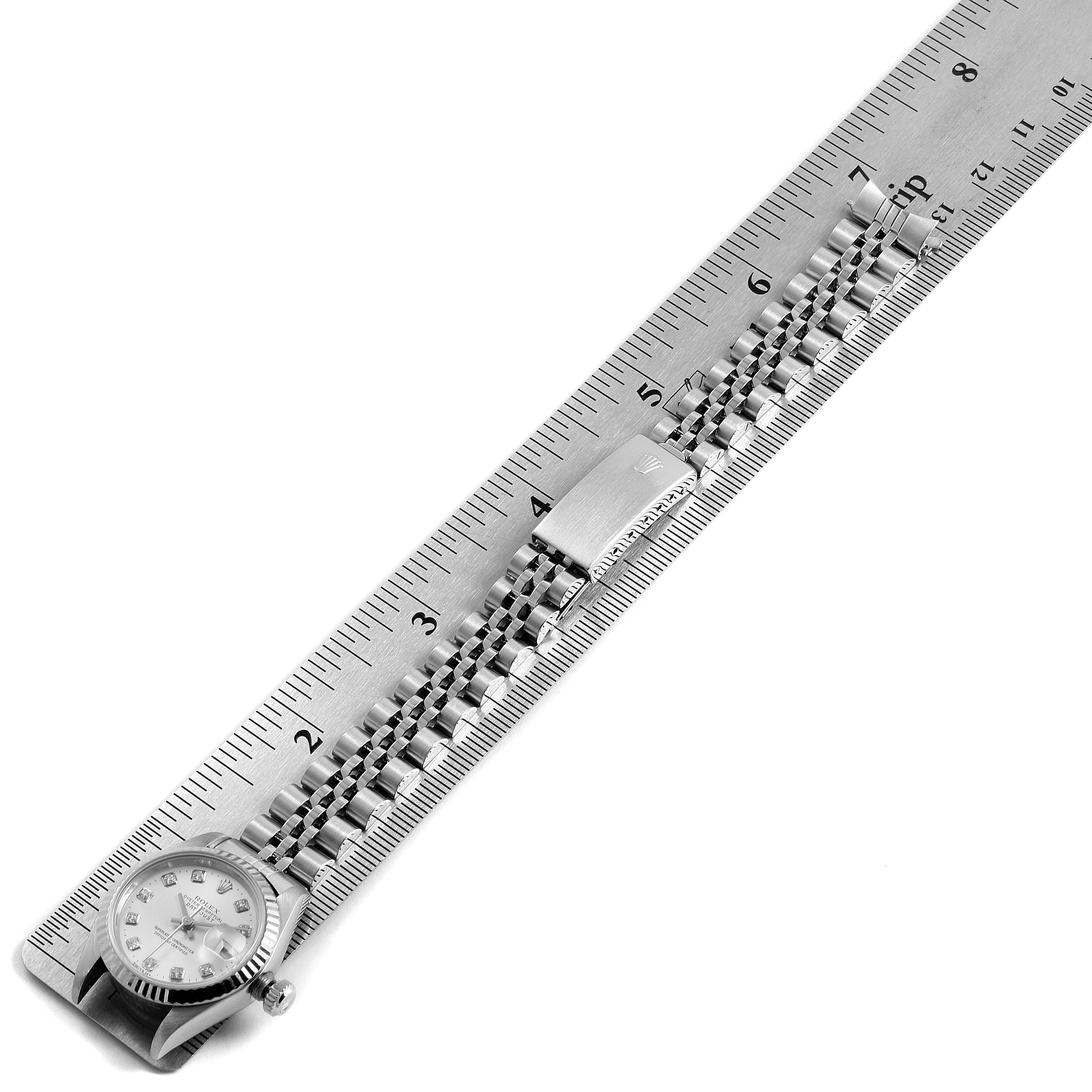 The image shows the Rolex Datejust 79174 Women's Stainless Steel Silver Dial 79174 Women's Stainless Steel Silver Dial watch laid flat against a ruler, highlighting the face, clasp, and metal bracelet.