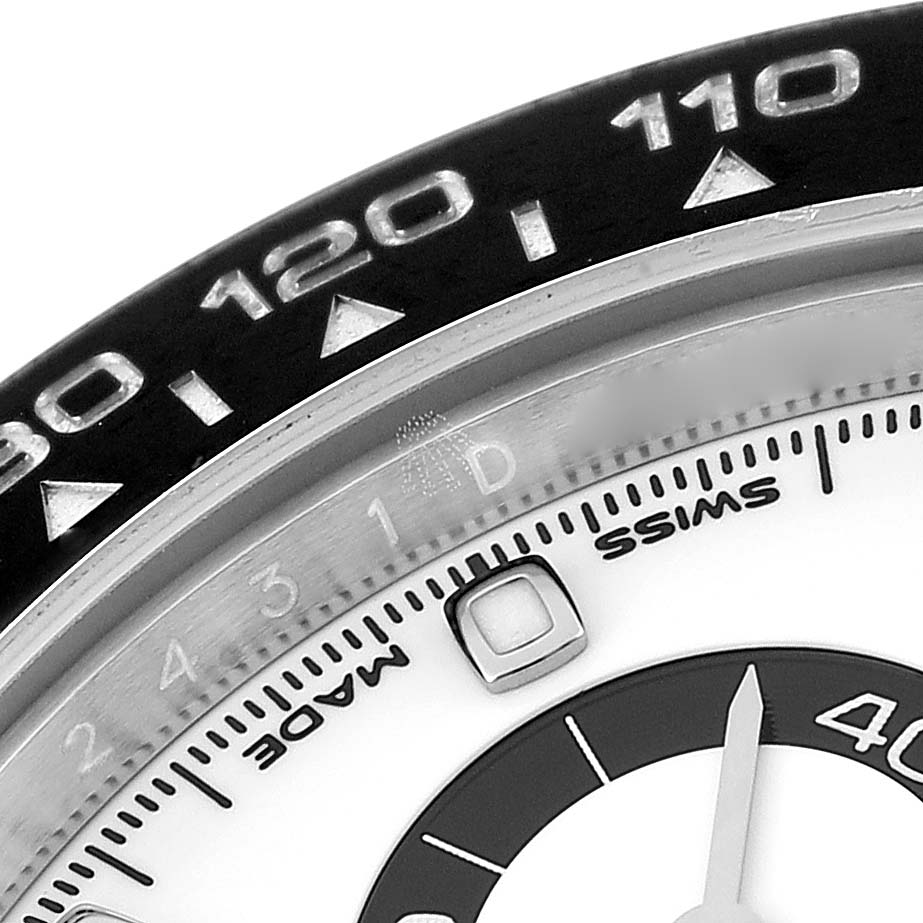This close-up of the Rolex Daytona 116500 Men
s Stainless Steel White Dial 116500 Men
s Stainless Steel White Dial watch highlights the bezel with tachymeter scale and a portion of the dial with minute markers.