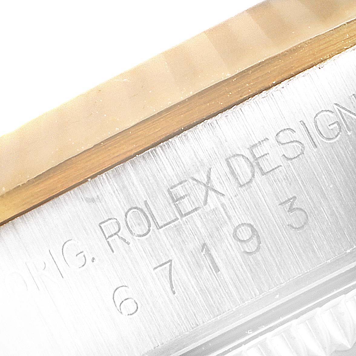 This close-up image shows the engraved serial number on the side of the case of a Rolex Oyster Perpetual 67193 Women's Steel and Gold (two tone) Black Dial 67193 Women's Steel and Gold (two tone) Black Dial watch.