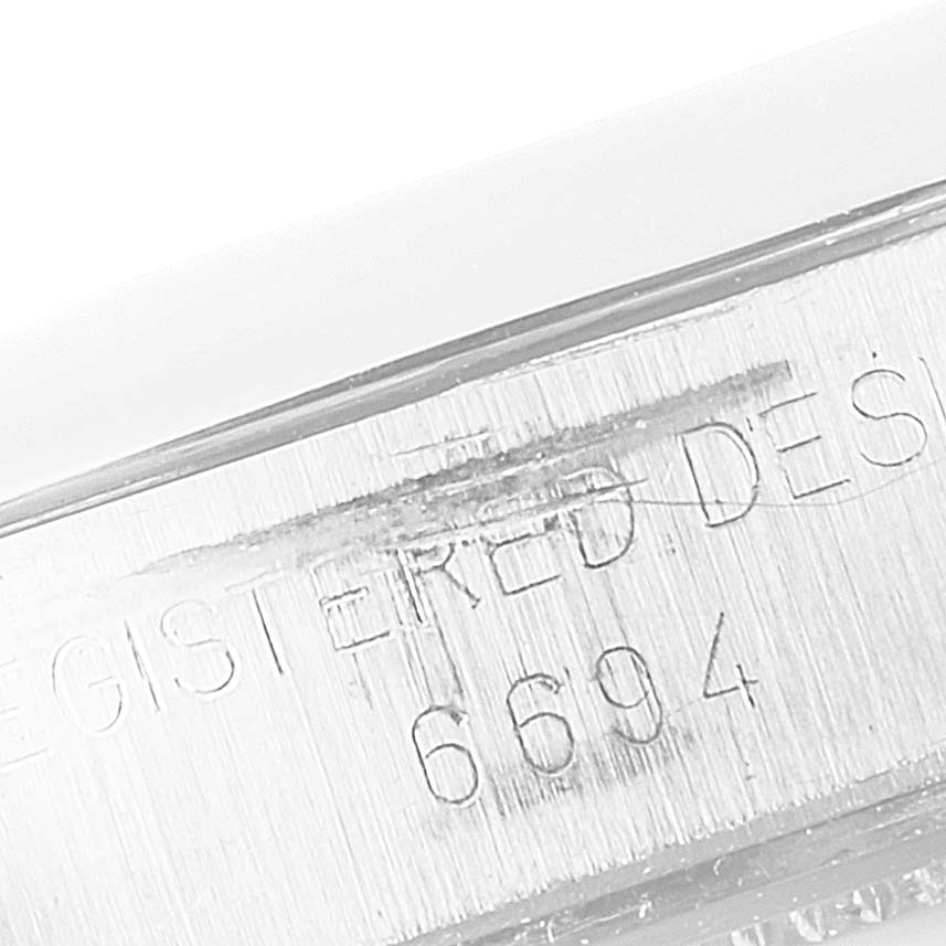 This image shows a close-up of the side of a Rolex Vintage Collection 6694 Men's Stainless Steel Silver Dial 6694 Men's Stainless Steel Silver Dial model, highlighting the engraved "REGISTERED DESIGN 6694."