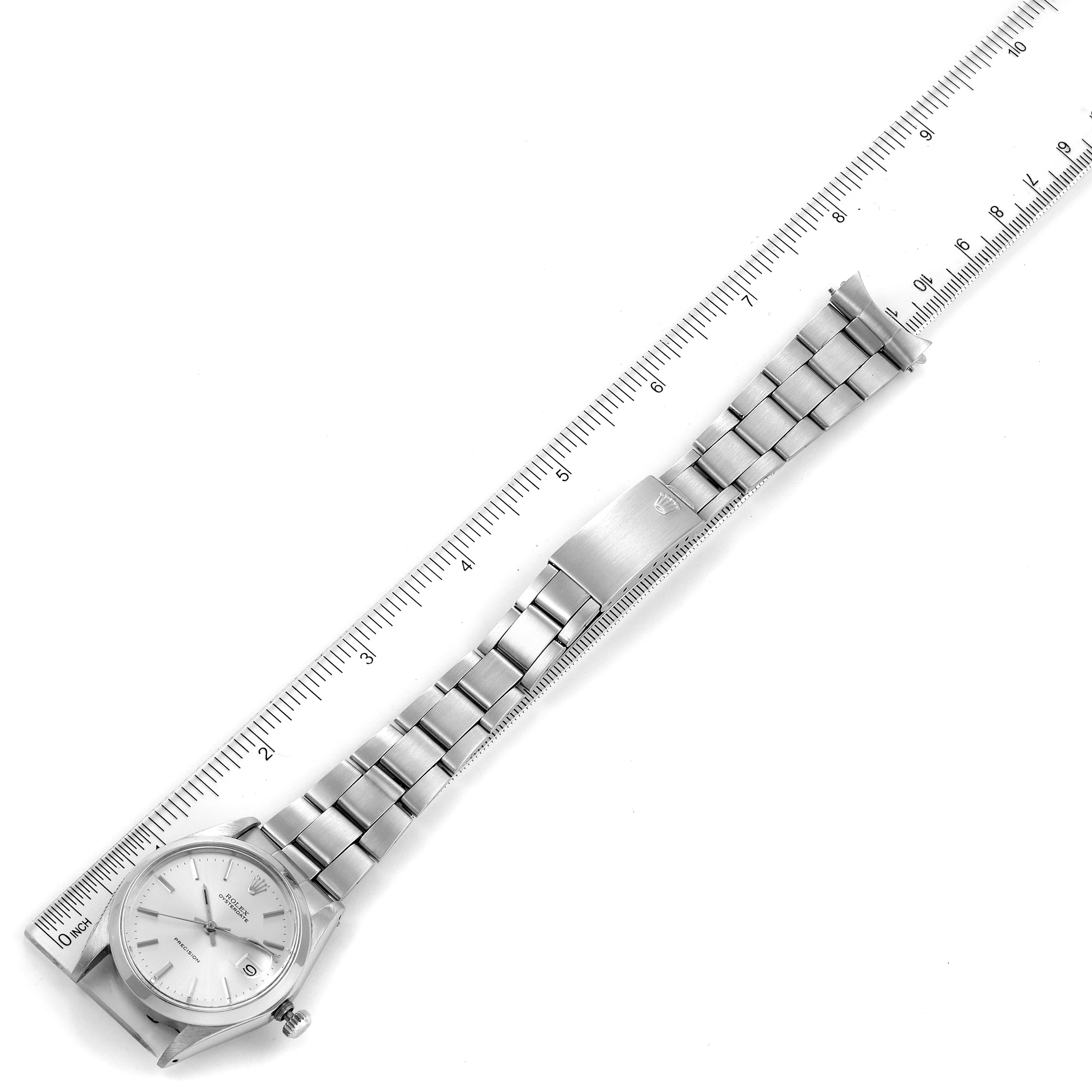 The image shows a top-down view of a Rolex Vintage Collection 6694 Men's Stainless Steel Silver Dial 6694 Men's Stainless Steel Silver Dial watch, including the face, bracelet, and clasp, next to a ruler for scale.
