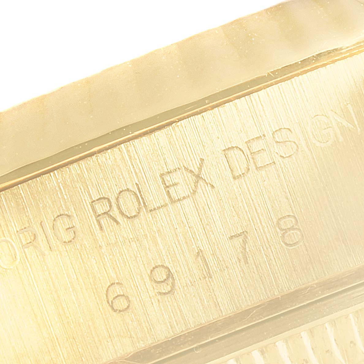 The image shows a close-up of the side engraving on a Rolex President 69178 Women's Yellow Gold White Dial 69178 Women's Yellow Gold White Dial model watch, featuring the serial and design numbers.