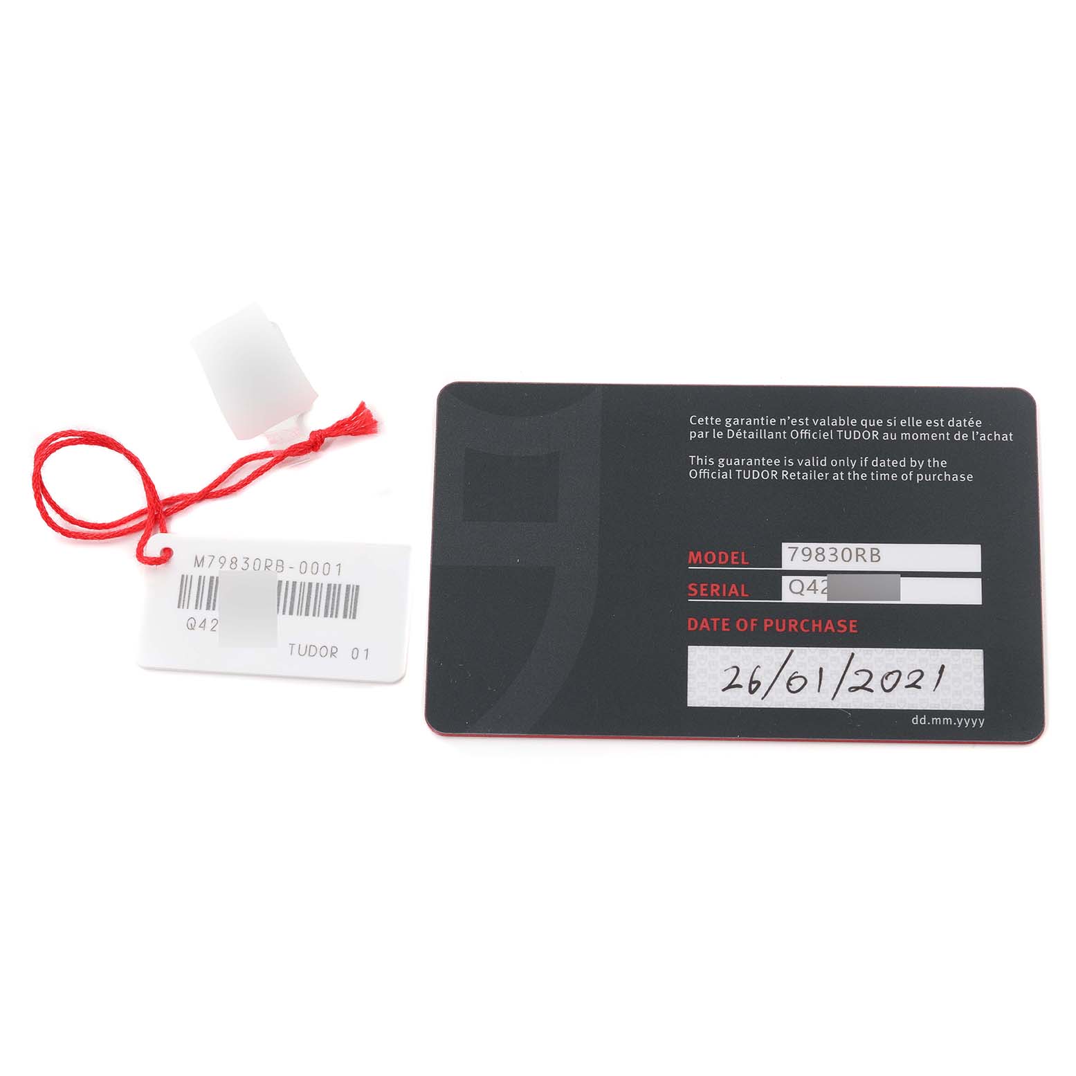 The image shows a Tudor Heritage Black Bay 79830RB Men
s Stainless Steel Black Dial 79830RB Men
s Stainless Steel Black Dial model tag, barcode tag, and warranty card from a top-down angle.