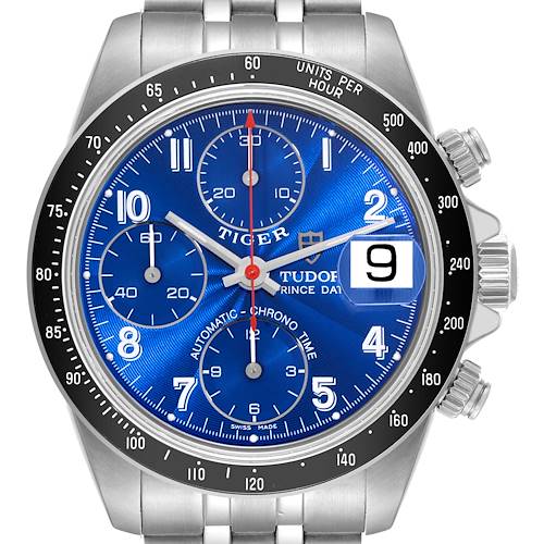 The image shows the dial and bezel of the Tudor Tiger watch, highlighting its blue face, chronograph features, and date window at 3 o'clock.