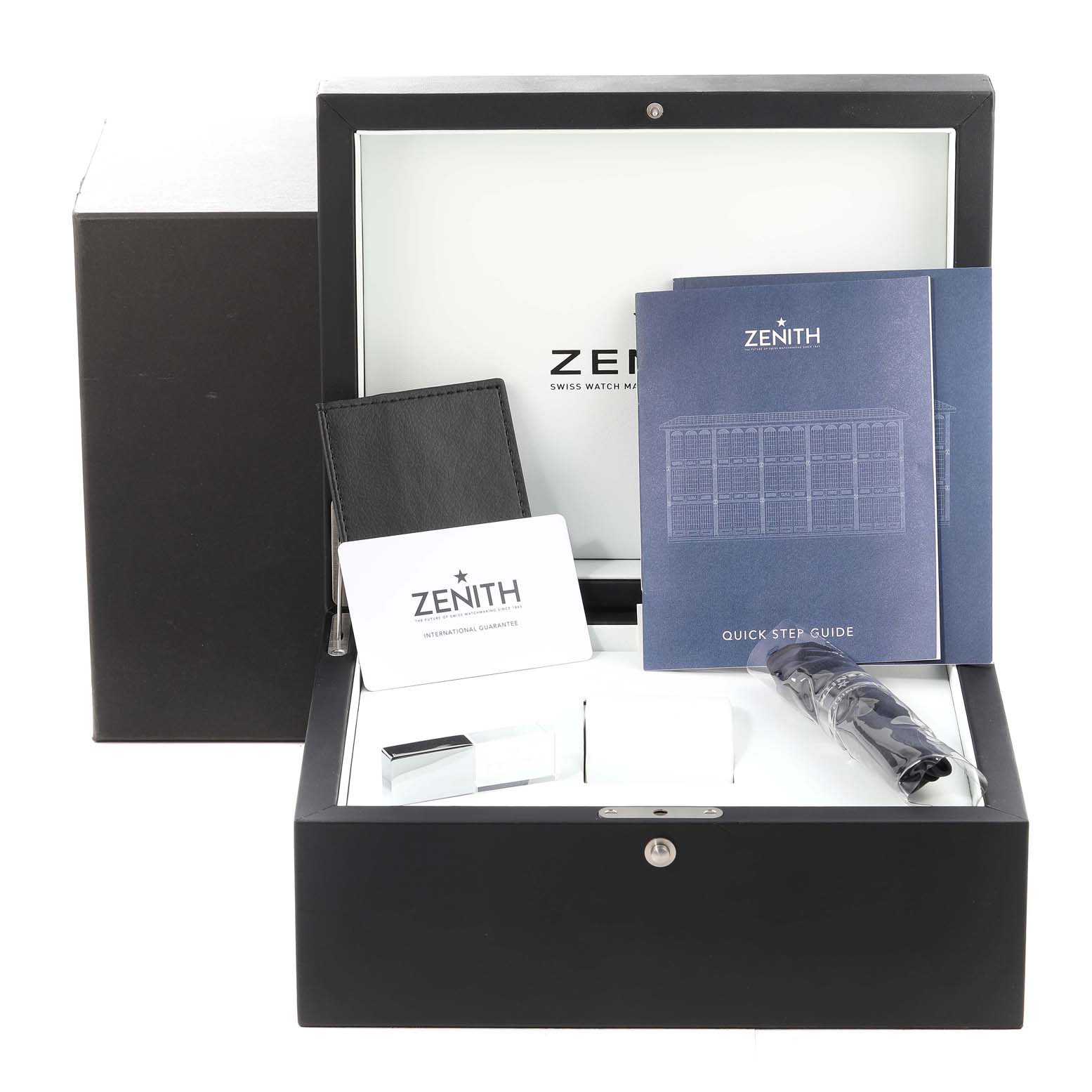 The image shows accessories for a Zenith Chronomaster 03.3100.3600/21.M3100 Men's Stainless Steel Black Dial 03.3100.3600/21.M3100 Men's Stainless Steel Black Dial watch, including a manual, warranty card, and other items inside a display box.