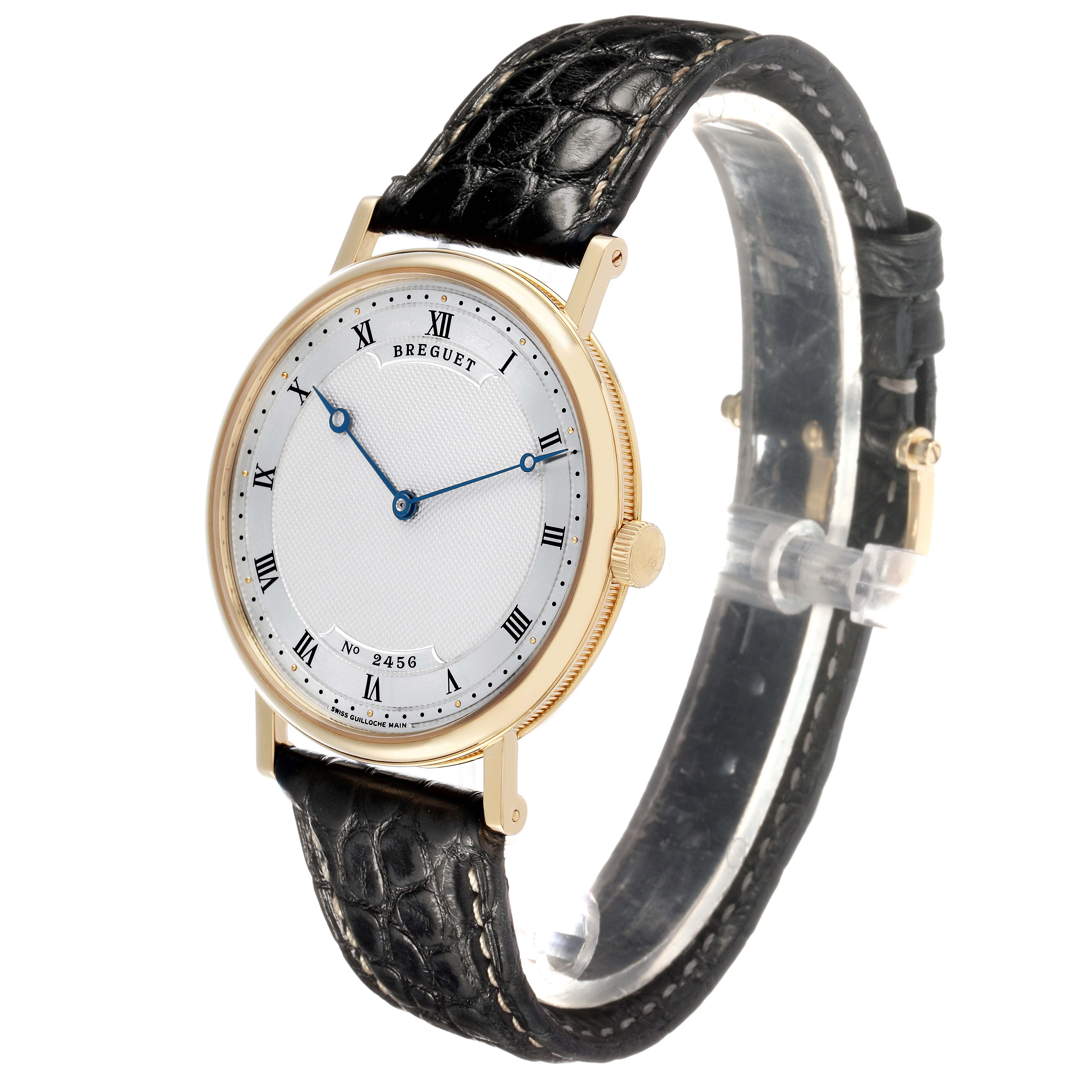 The Breguet Classique 5157BA Men's Yellow Gold Silver Dial watch is shown at an oblique angle, highlighting its face, blue hands, Roman numerals, and leather strap.